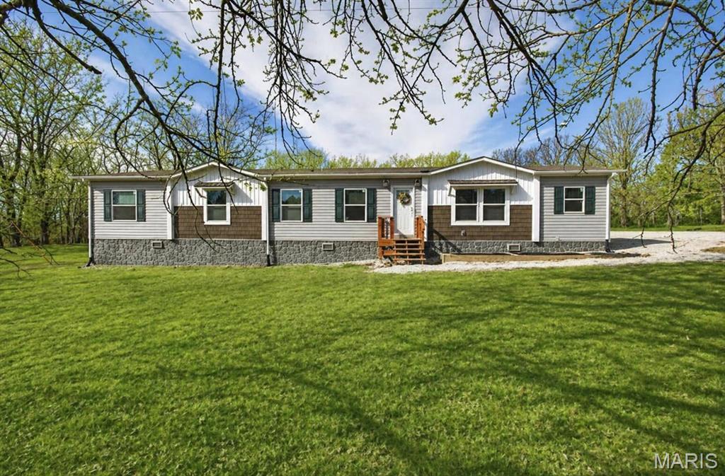 Spacious country living meets modern comfort in this beautifully designed 5-bedroom, 2-bath manufactured home set on acreage. Inside, you'll love the open-concept layout featuring a bright and airy living space, a generous dining area, and a stunning kitchen complete with a large island--perfect for family gatherings or entertaining. A walk-in pantry with a charming sliding barn door adds both style and function. The thoughtfully designed floor plan offers privacy, with the expansive primary suite situated on one side of the home. Enjoy a large walk-in closet and a luxurious ensuite featuring a walk-in shower and oversized soaking tub. On the opposite side, you'll find four additional bedrooms, a full bath, and a convenient laundry area with direct access to the mudroom--complete with built-in cabinets, coat, and shoe storage. This home is packed with practical upgrades, including a water softener, private well, newer septic system, and a backup generator for peace of mind. Step outside to enjoy the serene setting: raised garden beds, a spacious back deck ideal for relaxing or entertaining, and a beautifully maintained, park-like yard perfect for gatherings or watching wildlife. The 960 sq. ft. shop offers incredible versatility with built-in cabinetry--ideal for a workshop, garage, or hobby space. An additional outbuilding provides even more storage or could easily serve as a chicken coop. With plenty of room to roam, play, and explore, this property also offers exciting potential for future expansion, including the possibility of adding another home. A rare opportunity to enjoy space, privacy, and functionality all in one!