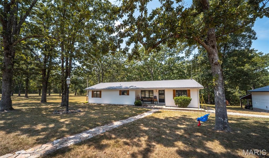 Enjoy the space and peaceful surroundings of country living with this inviting 3-bedroom, 2-bathroom home situated on 2.44 acres near the South Gate of Fort Leonard Wood. Offering a beautiful combination of open yard and wooded areas, this property provides the privacy and breathing room you’ve been looking for while keeping you conveniently close to Fort Leonard Wood and thousands of acres of Mark Twain National Forest. A welcoming covered front porch sets the tone for relaxed rural living and provides the perfect spot for morning coffee or unwinding at the end of the day. Inside, the open living, dining, and kitchen layout creates a comfortable flow for everyday life and entertaining. A cozy gas fireplace anchors the living room, making it an inviting gathering place throughout the seasons. The spacious kitchen offers plenty of cabinet and counter space, giving you room for meal prep, storage, and hosting. Retreat to the primary suite, complete with a walk-in closet and private bathroom featuring both a relaxing Jacuzzi tub and separate shower. Step outside onto the large rear deck where there’s plenty of space for grilling, entertaining, or simply enjoying the peaceful setting. The 2.44-acre lot offers a nice-sized yard along with wooded areas that add privacy and natural beauty. A large detached garage with lean-to provides valuable space for vehicles, equipment, storage, hobbies, or a workshop. If you’re searching for a large lot, well maintained home, and convenient access to the Fort Leonard Wood South Gate, this property offers an ideal combination of comfort and country living. Schedule your private showing today and experience it for yourself!