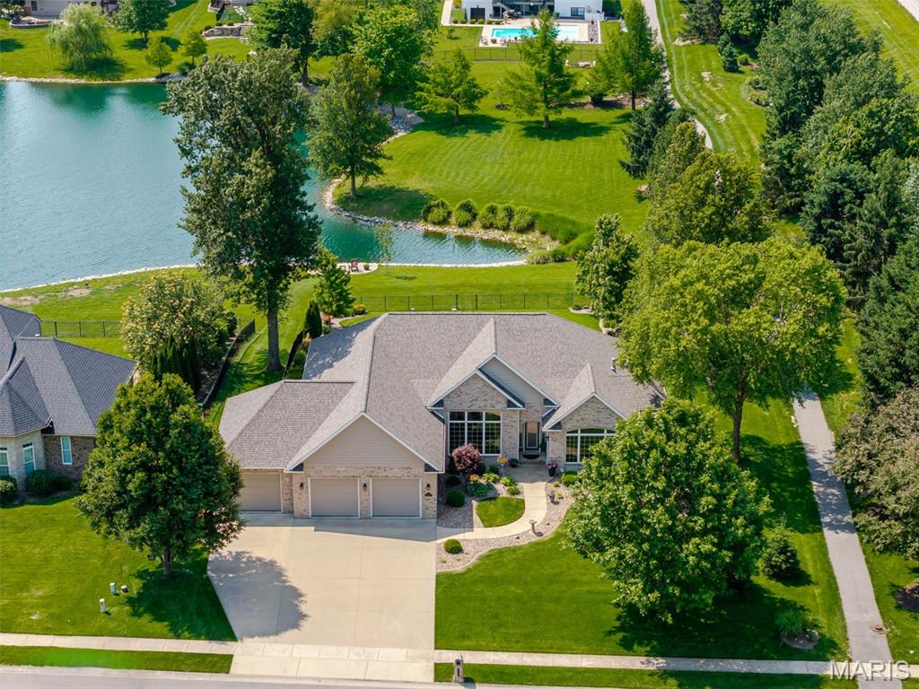 Elegance and refined lakeside living defines this meticulously maintained home in desirable O’Fallon’s Braeswood Estates. Set against breathtaking lake views, this exceptional custom built 4 bedroom, 3 bath home offers a thoughtfully designed open-concept layout with a desirable split-bedroom floor plan. Spacious primary bedroom suite is a private oasis, featuring coffered ceilings, dual walk-in closets, and a spa-like bath with soaking tub and walk-in tile shower with dual shower heads. From the moment you enter the welcoming foyer, you’re led into the natural light filled great room, where soaring vaulted ceilings, rich hardwood floors, and expansive windows perfectly frame stunning views of the lake and beautifully landscaped backyard. Striking see-through fireplace seamlessly connects the great room to the gourmet kitchen ideal for both everyday living and entertaining. Chef’s dream kitchen is the heart of the home, featuring a large granite center island, quartz countertops, stainless steel appliances, and abundant custom cabinetry. A sunny breakfast room offers the perfect spot to enjoy morning coffee with peaceful water views. Formal dining room provides space for memorable gatherings, while a dedicated home office makes remote work effortless. An open staircase with a dramatic windowed atrium leads to an entertainer’s dream walk-out basement. Here you’ll find a massive recreation room, a wet bar with wine cooler and mini refrigerator, and a cozy family room with its own fireplace. Basement also features 2 large unfinished areas for all of your storage needs. Step outside to a patio with a Sunesta retractable shade, custom firepit, immaculately maintained landscaping surrounding inground saltwater pool and fenced backyard making it the perfect private paradise. Enjoy peaceful lakeside living with a private charming sitting area perfect for unwinding with a book or simply enjoying the tranquil water views.  Located in the O’Fallon School District with convenient access to SAFB, I-64, St. Louis, shopping, dining, parks, and local wineries this home offers both luxury and convenience. With a new roof (2026), new HVAC system (2024), and evident pride of ownership throughout, this home presents exceptional care and attention to detail. List of all renovations and upgrades is available. In O’Fallon School District and minutes to SAFB, I-64, St. Louis, dining, shopping, parks, and local wineries. This is an Amazing Home for an Amazing Family. Call and tour today!