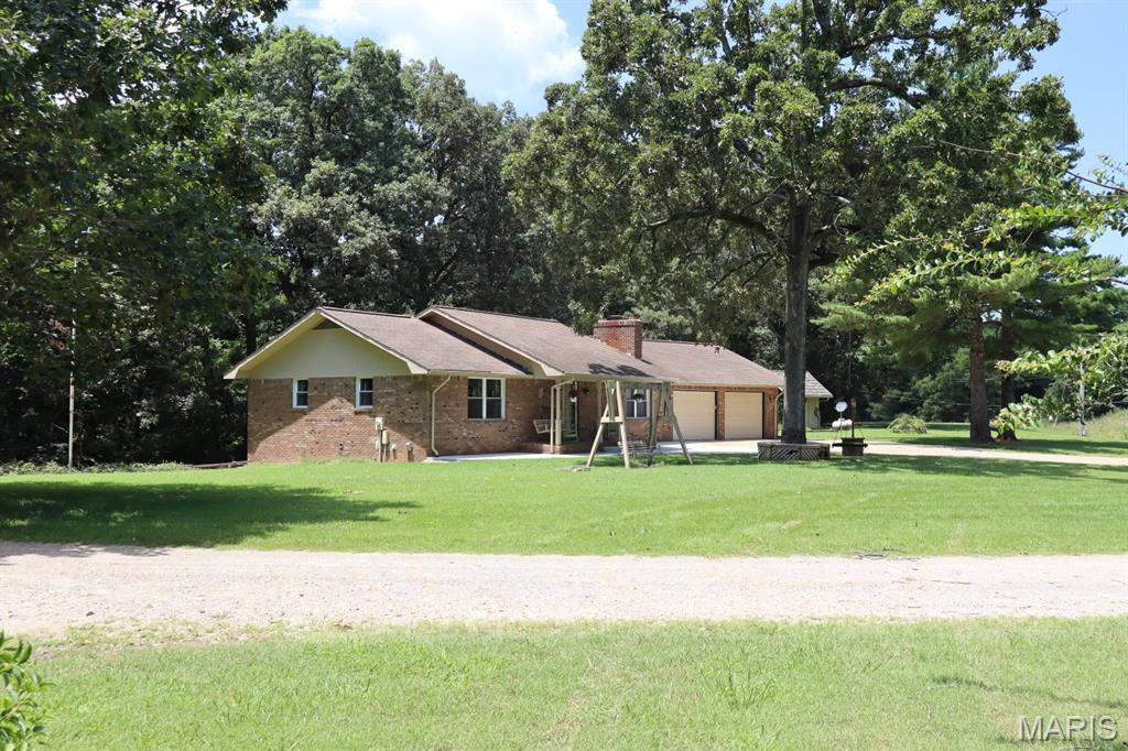 Sitting on the outskirts of Dexter, you will find this home nestled in the woods, but still along a paved road to town.  It has a front yard you can admire under the covered front porch or relax and enjoy the wildlife visiting from the woods behind you.  Inside, you'll find a comfortable-sized living room, a large kitchen with a separate dining area, a full bathroom, and a sunroom over-looking the deck.  The kitchen is complete with a bar for extra guests, a built-in desk, refrigerator, dishwasher, range top, a double oven for extra baking or entertaining, and ample storage. This home offers an over-sized, primary bedroom with a dream closet!  It's a large, walk-in, custom-designed closet with a place for clothing and shoes located on the main level.  Walk directly out the sunroom to the deck or walkout the basement family room to the covered patio.  The basement includes a large family room with a gas fireplace which could be converted back to woodburning.  There is a full bathroom, 2 bedrooms with built-in cabinets for clothing and a desk, and the laundry/maintenance room.  Outside, you will find a small, fenced area, perfect for pets, which can be removed if you prefer.  Under the deck, you will find a couple of hidden gems!  One is a small storage area for outdoor equipment and the other is a woodworking shop!  2 small outbuildings and an attached, two-car garage.  If all this isn't enough, step across the lane to your 30 x 24 shop and RV parking pad.   Call today for your personal tour.