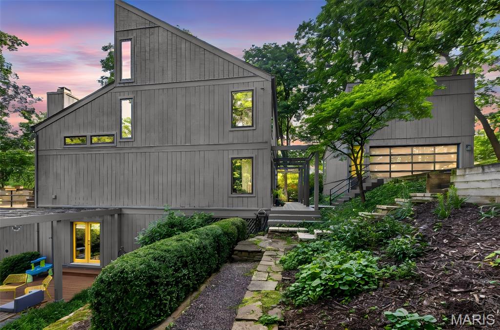 Welcome to your Hillside Hideaway — a striking contemporary retreat built into a wooded hillside in Sunset Hills, backing directly to Powder Valley Conservation Area. This is a home that doesn't sit on its lot so much as grow out of it: walls of glass, soaring vaulted ceilings, and multiple decks that step down into the trees, blurring the line between inside and out at every turn.

The main level opens into a light-filled, open floor plan made for gathering, anchored by a chef's kitchen with floor-to-ceiling custom cabinetry, Wolf and Sub-Zero appliances, and heated floors. A glass-wrapped breakfast nook and a four-season sunroom place you right in the canopy year-round, while a wood-burning fireplace and direct deck access make everyday living effortless.

Upstairs, three private bedrooms — each framing its own view of the woods — enjoy vaulted ceilings and an airy, oversized feel, while remaining open to the living space below. The primary suite offers an updated, heated-floor bath, and two additional bedrooms share a jack-and-jill bath.

The finished walk-out lower level adds even more room to live, with a bonus living area, a built-in wine rack, and flexible space for a family room, office, or gym. Two more decks extend the living outdoors — one with a pergola and fireplace, the other home to a brand-new custom cedar sauna.

Beyond the home, tiered stone gardens reward the active gardener, a custom-built clubhouse delights the youngest adventurers, and an oversized garage comes ready with a custom workbench. Extensive recent updates — including new Pella windows, foundation reinforcement, and fresh interior finishes — mean the big-ticket items are already handled.

All of this in the sought-after Lindbergh School District, tucked down a private drive yet just minutes from the shops and restaurants of Sunset Hills and historic downtown Kirkwood. Seclusion like this usually means a long drive home. Here, it doesn't.
Hillside Hideaway is the rare home that has to be experienced to be understood and appreciated in person.