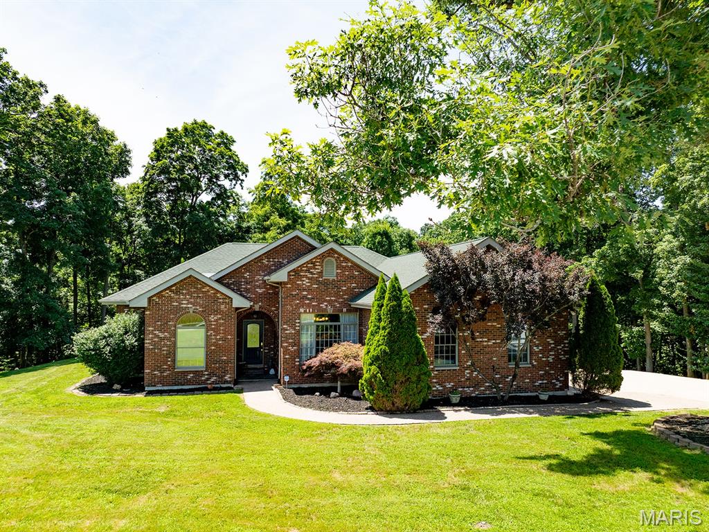 Step inside this single-owner home that has been meticulously maintained offering custom finishes such as a stone crafted fireplace, custom oak cabinetry, and stainless steel appliances.  Surrounded by a mix of oak and walnut trees, nestled on 4.7 peaceful acres, you'll find this solid brick, red-iron home.  Enjoy peace of mind with this metal frame structure that's engineered for extreme durability and storm resistance.  All interior walls are non-load bearing offering limitless potential and design flexibility.  1 ft (12-inch) thick walls ensure this home is energy-efficient and built to last!  Enjoy low utility bills thanks also in part to the all electric Geothermal System.  
Step into the spa-like master bath featuring a smart LED mirror, walk-in tiled shower and sleek freestanding soaking tub designed for ultimate relaxation.  You'll discover a seamless indoor-outdoor flow as you walk through French doors that lead onto a massive, low-maintenance, 41x17 ft exposed aggregate concrete patio offering an upscale slip-resistant texture.  This open-air retreat is perfect for summer barbecues, and peaceful stargazing evenings.  
The lower level combines a spacious living area and custom dry bar.  Also featuring 2 private sleeping rooms and a full bathroom offering comfort and convenience for family and guests.  Step outside as your private recreational oasis awaits.  You'll discover a peaceful creek and an exclusive UTV/side-by-side tract that offers outdoor adventure right in your own backyard!  Gardeners will love the attached walkout greenhouse.  Positioned off the lower-level basement exit, this sunny structure is ready for your green thumb.  
This sturdy, well built home will go fast so call today for your private tour!