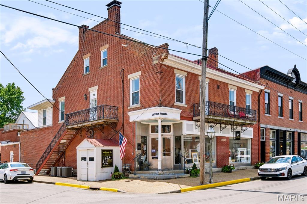 Historic Downtown Ste. Genevieve Commercial Building with Live/Work Potential Opportunity awaits in the heart of historic downtown Ste. Genevieve! Located just steps from the area’s beautiful historic church, museums, restaurants, shops, and other downtown attractions, this one-of-a-kind building offers over 5,000 square feet of space and an incredible combination of historic character, recent improvements, and flexible possibilities. Currently operating as an art gallery, the main floor offers a large, open floor plan with tall ceilings, refinished original hardwood floors, track lighting, ceiling fans, and a recently updated bathroom. The spacious rear portion of the building includes a workshop and office area, providing plenty of room for an artist, craftsman, retailer, studio, or other creative business. The upper levels open the door to an entirely different opportunity. The second floor was previously used as a residence and could easily be converted back into a comfortable living space, making this an ideal candidate for a live/work arrangement. Accessible by a large staircase with custom railings built and designed by a local artist, it features a full kitchen with an abundance of cabinet space and appliances, two full bathrooms, a laundry room with washer and dryer hookups, and two bedrooms with excellent natural light. The bedrooms feature large closets, built-in drawers, and beautiful decorative millwork. One bedroom also provides access to a balcony overlooking the intersection of Market and 3rd Street, with views toward the historic church, courthouse, and downtown murals. The main living area on the second floor showcases the building’s original 1876 hardwood floors, beautifully refinished and full of character. There is also a separate exterior entrance if a buyer wanted to completely separate the gallery from the residential space making it ideal for a possible short term rental. The third floor is currently used for storage and includes two additional rooms with temperature control. With the right vision, this space could potentially be converted into two additional bedrooms, studios, or offices. The building has also benefited from numerous significant recent improvements, including a new roof (installed in May 2026), tuckpointing, electrical and plumbing updates, new HVAC units, and the addition of an ADA-compliant ramp and bathroom—a particularly valuable and uncommon feature in a historic downtown building. Outside, the building has the historic charm you would expect from downtown Ste. Genevieve, including historic masonry, large windows, balconies, and a distinctive stainless steel entryway. Whether you’ve dreamed of opening your own art gallery, boutique, studio, shop, or creative business, or you’re looking for a unique live/work property in one of Missouri’s most historic communities, this property offers an opportunity that is truly hard to duplicate. Historic charm. Recent improvements. Incredible location. Endless possibilities. Come see what makes this downtown property so special!
