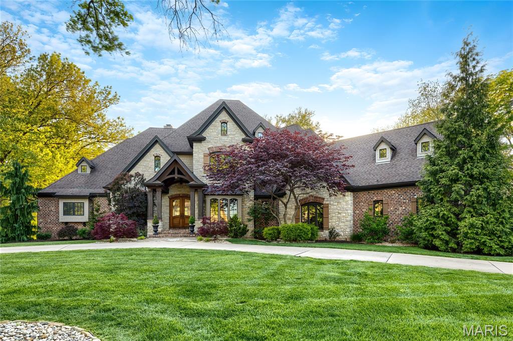 An impressive stone, brick & cedar elevation defines the rustic architecture of this Colorado-inspired Estate home. Open floor plan features handscraped Asian walnut flooring, soaring ceilings, detailed trim work & plantation shutters. Vaulted slate porch entrance with 8’ mahogany double doors leads to impressive 2-sty foyer highlighted by dramatic curved staircase, private study, elegant dining room framed by arched entryways and stunning great room with box beam ceiling, floor-to-ceiling stone fireplace, built-in bookcases & 2-sty wall of windows. Designer kitchen with knotty Alder cabinetry, granite countertops, premium stainless steel appliances, 8’ crescent center island & butler’s pantry adjoins light-filled breakfast room & vaulted hearth room with stone fireplace, granite bar & atrium doors that open to screened porch. Coffered primary bedroom suite with 2 customized walk-in closets & luxury bath with jetted tub & shower spa provides an appealing retreat. Front & rear staircases access 3 additional ensuite bedrooms & bonus room. Lower Level entertainment space includes recreation room with wet bar, family room with woodburning fireplace, media room & game room plus hobby room, workout room & half bath. Situated on a tree-lined 1+ acre lot with pool, covered patio & open patio with full-height fireplace.