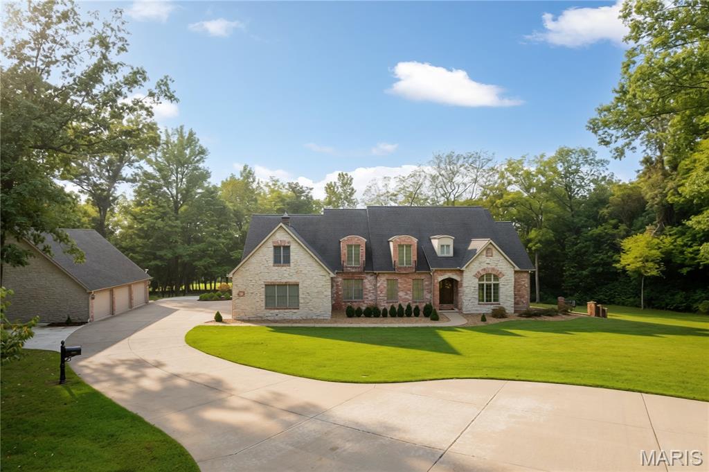 A sweeping, tree-lined drive leads you home to this impressive brick-and-stone beauty, perfectly positioned on over 3 acres of gorgeous views and wooded trails. Inside, the home is filled with character and craftsmanship. Warm hardwood floors, graceful arched openings, detailed millwork and iron stair railings create an inviting first impression. The spacious kitchen features abundant custom cabinetry, granite countertops, stainless appliances, and both an island and breakfast bar. Sunlight pours through oversized windows throughout the home, while the multiple living spaces offer room to spread out without losing that warm, comfortable feeling. Both eat-in kitchen and formal dining, a great room with a cozy fireplace that passes through to the covered deck, a dedicated study with beautiful architectural detail, both main and upper level laundry, and a landing den that serves as an upper level hangout. The primary suite feels like its own getaway with a dedicated fireplace, tray ceiling, and a generous bath complete with dual vanities, a jetted soaking tub, and tiled cave shower. Head downstairs to the walkout basement for entertainment heaven: an incredible custom bar, family room, two guest rooms, a John Deer and hobby room, a cedar closet, and more! Additional features include zoned irrigation system, whole home generator, and geothermal heat and air. And then the most recent addition…  an unbelievable detached FOUR-BAY garage/shop. Whether you’re a car enthusiast, collector, hobbyist, need serious workshop space or simply dream of having room for all the toys, this is the kind of setup that is incredibly hard to find. Over 4 acres, mature trees, privacy, beautiful surroundings, an impressive home and a dream garage/shop… this property doesn’t just give you more space, it gives you a whole different way to live.