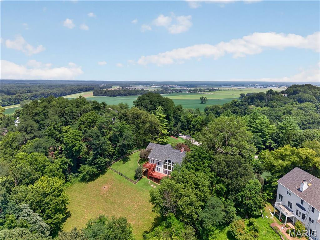 LOVELY atrium ranch home in the highly desirable Wild Horse Bluff subdivision situated on a sprawling, secluded, LEVEL to sloping, 3+/- acre lot surrounded by mature trees. This custom home offers a private country feel just minutes from ample amenities & a SPECTACULAR view of the Chesterfield Valley, which is a must see! 4 Bedroom, 4 full bath home featuring 4,288+/- SqFt, 9’+/- ceilings & job-finished wood flooring through most of main level. Partially covered, expansive, flagstone front porch greets you as you step inside the entry foyer. Living room boasts a 14’+/- vaulted ceiling, wood burning fireplace & a wall of windows allowing plenty of natural light. Kitchen offers custom cabinetry, coffered ceiling, center island, breakfast bar, tile backsplash, pantry & butler’s pantry w/prep sink. Breakfast room features a 12’+/- vaulted ceiling & a bay window w/wall of windows. Primary suite with carpet, 14’+/- vaulted ceiling, large custom walk-in closet & ensuite full bath with French door entry, tile flooring, shower w/glass door, double single sink vanity, jet tub & private commode. Additional main level bedroom with carpet, slide closet & shares hall bath with a shower/tub & single sink. Office, dining room, sitting room, & laundry closet completes the main level. Walk-out lower level extends living quarters that feature a family room with a wood burning fireplace, wet bar, built-in bookcases, indoor atrium & a sliding glass walk-out to lower deck. 3rd & 4th Bedroom w/large walk-in custom closets & 1 w/ensuite bath, other shares hall bath. Unfinished utility room for additional storage space. Outside, enjoy an AWESOME level/gently rolling fully fenced-in backyard, FABULOUS/spacious upper & lower level wood decks, PERFECT for family gatherings, & a 3-car attached garage.