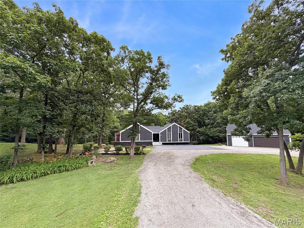 Welcome to your own private retreat on 5.25 beautiful wooded acres just outside Bowling Green! This spacious 4-bedroom, 3-bath home offers over 3,700 sq. ft. of living space, where quality craftmanship, spacious living areas and scenic surroundings come together to create an exceptional place to call home.  Recent improvements include a new roof, gutters and freshly painted exterior on both the home and detached 3 car garage.  Also, new garage door, a new composite front porch, and asphalt driveway - providing outstanding curb appeal and peace of mind.  Not only that - there is a 24 x 24 concrete pad behind the detached garage for basketball, outdoor seating or anything you can imagine.

From the moment you walk through the front door, you'll be welcomed by numerous updates that make this home truly move-in ready.  The updated kitchen includes custom Amish-built cabinets featuring premium soft-close doors and drawers, built in double oven and microwave and rollout shelving for ease of accessibility.  Enjoy the open floor plan with vaulted and beamed ceilings, luxury vinyl plank flooring, and more custom Amish built cabinets in the Drop-Zone and pantry.  Beautiful concrete countertops in the kitchen, quartz countertops in all 3 bathrooms, updated showers, Colorado teak dimensional accent walls, and a stunning wood-burning fireplace to keep the house warm all winter long.   Enjoy watching the wildlife with a cup of coffee on the covered deck with ceiling fan right out the master bedroom new sliding glass door!  The walkout lower level features a second primary suite, theatre room with a projector and huge commercial screen, large family room, a full bathroom, and tons and tons of storage.

Car enthusiasts, hobbyists, and entrepreneurs will love the garage space! The property includes a 2-car attached garage plus a climate controlled 3-car garage with 8 foot tall doors, a workshop area, and man-cave loft above, offering endless possibilities.

Enjoy the outdoors from the covered front porch, expansive deck, or large patio while taking in the peaceful wooded surroundings. Additional features include a circular driveway, trails to the back woods, a creek deer like to visit, public water, and convenient access to Bowling Green amenities. A rare opportunity to own an updated property with acreage, privacy, and exceptional garage space just outside the city limits.