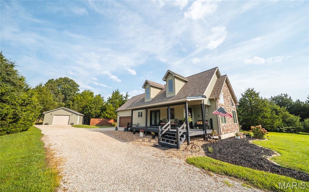 Welcome home to this beautiful custom-built 3-bedroom, 2-bath, 1.5-story home nestled on approximately 2.93 acres. This unique floorplan offers an impressive living room featuring vaulted ceilings, oversized windows that fill the space with natural light, and a spectacular floor-to-ceiling stone gas fireplace as the centerpiece. Gorgeous rock accents and a complementary stone archway create a warm, inviting atmosphere. The spacious kitchen and dining area is designed for both everyday living and entertaining, with an abundance of custom cabinetry, stainless steel appliances, a large center island with a slide-in stove/oven, and ample workspace. A large walk-in pantry with a pocket door adds even more storage. The private upstairs master suite serves as a peaceful retreat, complete with a spacious bedroom, walk-in closet, and a full en-suite bath. On the main level, you'll find two generously sized guest bedrooms, a full guest bathroom, and a large laundry room with ceramic tile flooring. There's an oversized 2-car attached garage with a built-in tornado shelter, a detached one car garage/workshop and a large, level yard backing to mature trees and beautiful landscaping. Built in 2014, this rustic home combines character, comfort, and modern conveniences in a peaceful country setting. Homes like this don't come along often—schedule your private showing today!