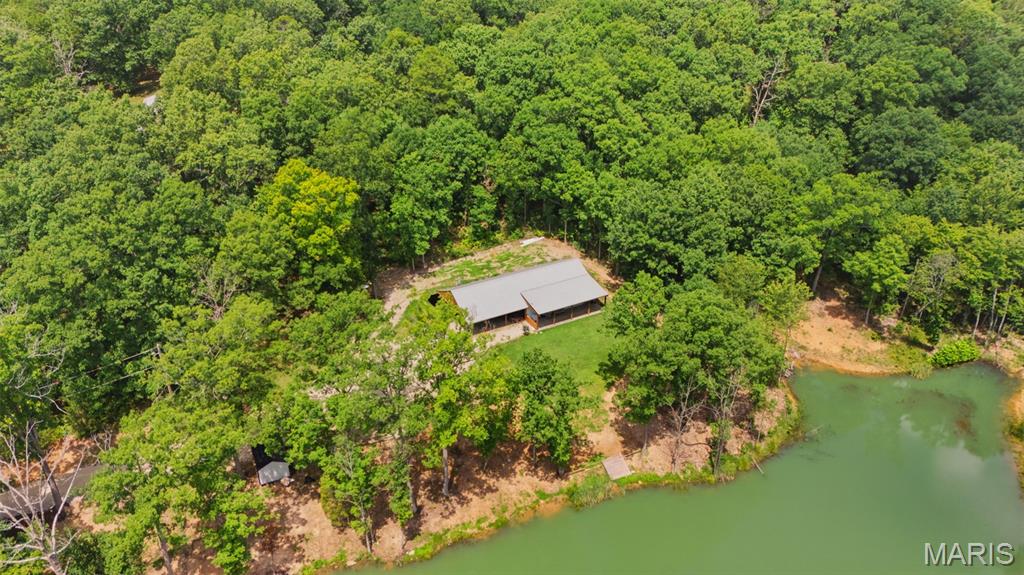 Headline: High-Efficiency Earth Home on 9+ Private Acres with Stocked Pond & RV Site!
Welcome to your ultimate private retreat! Built in 2023, this unique earth home. The home features 2x6 framing on the front wall, thick blown-in insulation, and a state-of-the-art HVAC system, resulting in incredibly low utility bills. Tucked away on over 9+/- private, serene acres, the property features a fully stocked 1-acre private pond, an abundance of local wildlife, and a dedicated camper parking spot complete with electric and water hookups only.
The exterior boasts a durable metal roof and siding, a 1-car attached carport, and a spacious covered front porch overlooking the water. Inside, you'll find beautiful, durable waterproof flooring throughout the expansive open floor plan. The living area showcases 9ft ceilings and beautiful wood ceilings, while the stunning kitchen comes equipped with stainless steel appliances. Bonus space alert: A partially finished 10x26 room off the carport is already rough-plumbed for a full bath and a large bedroom, offering an easy path to extra square footage!