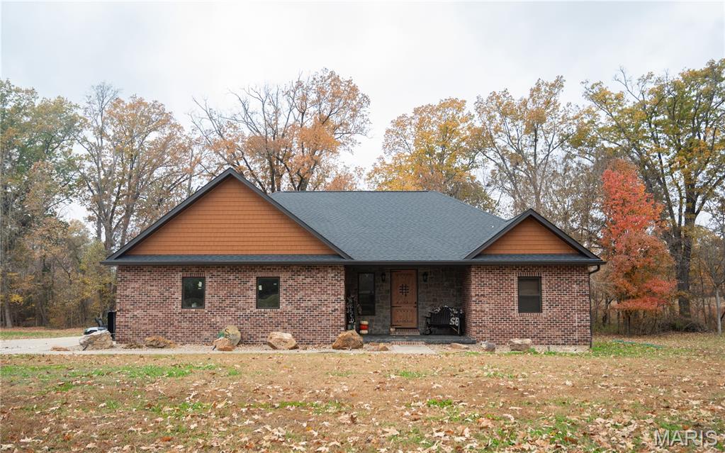 Custom brick and stone home on nearly 3 acres offering high-end finishes and rustic charm. Inside, the gourmet kitchen features Cambria quartz countertops, a copper farmhouse sink, maple-glazed cabinets, ledgestone pillars, and a full KitchenAid appliance suite. The home features two master suites, each with a cedar-framed bed, a walk-in closet, and hardwood floors. A spacious third bedroom, currently used as a study, and a versatile bonus room, ideal for storage or a nursery, provide additional flexibility. Both master suite bathrooms are beautifully finished with custom cabinetry, stone sinks, quartz countertops, and tiled showers. The living room offers a warm, rustic feel with a custom stone fireplace wrapped in cedar, vaulted ceilings with custom beams, and a knotty alder front door. Enjoy the outdoors with concrete front and back porches, a 30x30 shop with a 10x30 overhang, and an oversized two-car garage. Quality craftsmanship and thoughtful design make this home a standout property in a peaceful country setting.
