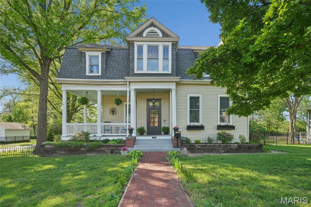 Majestic 2-story residence set on rare acreage in a prime Webster Groves location, offering over 3,500 sq ft of beautifully appointed living space. Originally built in 1904, this exceptional home showcases timeless architectural character paired with thoughtful updates and quality improvements, creating a seamless blend of historic charm and modern livability—all just minutes from everything St. Louis has to offer.  A grand entry foyer sets an impressive tone with exquisite millwork, Bird’s Eye Maple hardwood floors, and soaring 10’+ ceilings. The foyer flows effortlessly into a sophisticated sitting room and expansive living room anchored by an 8’ custom oak mantel and fireplace with heatilator. An elegant formal dining room featuring a bay window and its own striking fireplace connects beautifully to the main living areas, offering both openness and definition for everyday living and entertaining.
The gourmet kitchen is designed with both style and function in mind, featuring granite countertops, stainless steel appliances, tile backsplash, double ovens, center island, walk-in pantry, and a light-filled breakfast room. A convenient laundry/mud room and powder room complete the main level.
Upstairs, the primary suite serves as a private retreat with its own sitting room and a spa-inspired bath showcasing quartz-topped vanities and a walk-in shower with dual shower heads and multiple spray features. Additional bedrooms are generously sized and highly versatile—ideal for home offices, creative spaces, or flexible living needs—along with an updated hall bath and continued tall ceilings.
The lower level offers excellent potential for future customization.
Notable updates include 42 Andersen vinyl windows, structural improvements with a transferable warranty, an oversized detached garage, freshly painted deck (2021), and a new water heater (2023)—enhancing both comfort and long-term value.
Outdoors, the property truly stands out. A welcoming wraparound porch and charming brick patio overlook expansive, tree-lined grounds, creating a private, park-like setting ideal for entertaining and everyday enjoyment. The detached oversized garage provides ample space for vehicles, storage, or hobbies. Rare acreage, timeless charm, and a sought-after location—all within walking distance to Old Orchard shops, restaurants, and Blackburn Park—make this a truly unique opportunity.