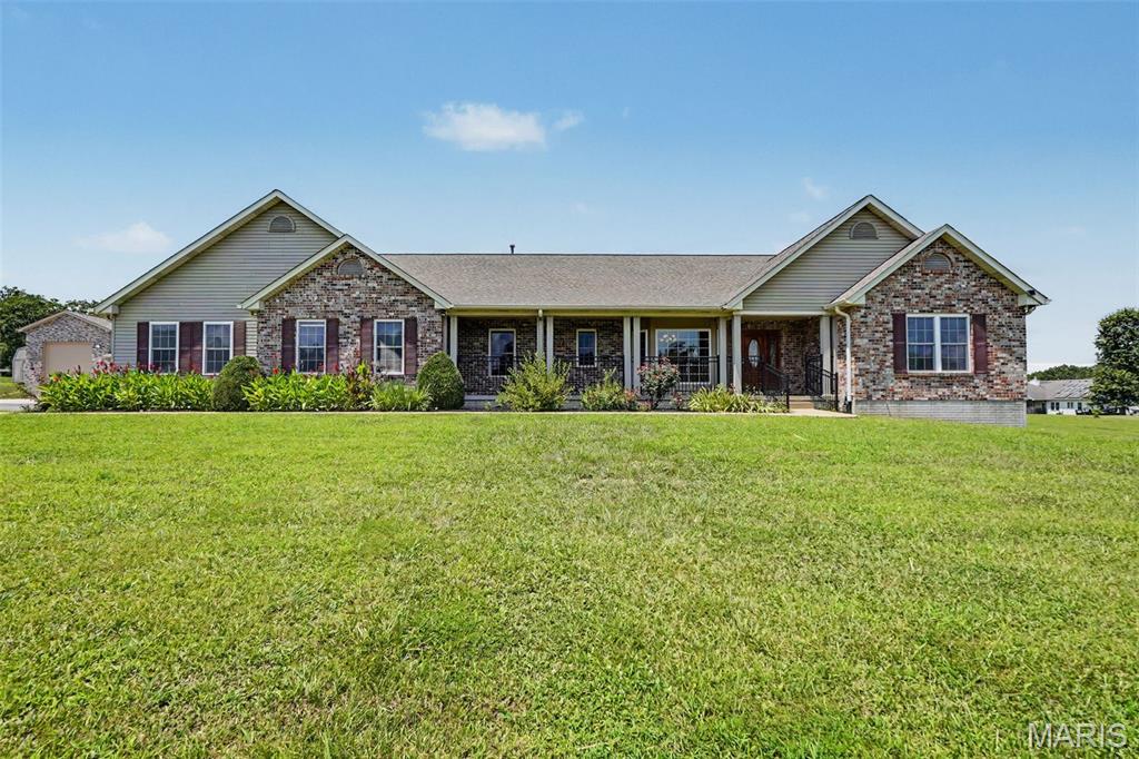 Set gracefully on three mostly level acres, this sprawling ranch offers a refined blend of comfort, craftsmanship, and space within the sought-after Festus School District. A welcoming front porch stretches across the facade, creating a serene vantage point over the meticulously maintained grounds. Inside, rich hardwood flooring flows throughout much of the main level, complemented by an open, light-filled floor plan accentuated with vaulted ceilings and expansive windows dressed in classic wood blinds. The entry foyer is both spacious and inviting, flanked by a formal dining room ideal for gatherings. At the heart of the home, the kitchen is thoughtfully designed with custom cabinetry, dual pantries, a substantial center island, and seamless connection to the breakfast room and living area. A charming bay window and built-in shelving add character and warmth to the breakfast space. A sunlit bonus room, surrounded by windows on three sides and framed by French doors, offers flexibility for a home office, sitting room, or creative space. The primary suite provides a private retreat, featuring a spa-inspired bath with whirlpool tub, separate shower, dual vanities, and a generous walk-in closet. Two additional bedrooms and a well-appointed bath with double vanities complete the main level. Outdoor living is equally impressive, with an expansive 38x15 deck—partially covered—overlooking peaceful acreage teeming with wildlife. The finished lower level adds versatility with a spacious family room, two additional bedrooms, full bath, and abundant storage. A truly exceptional feature of this property is the newly constructed custom detached garage/outbuilding—designed to accommodate up to multiple vehicles plus an RV. Fully equipped with its own HVAC system, WiFi connectivity, and electric, this remarkable space offers endless possibilities for collectors, hobbyists, or those seeking a premium workshop or recreational retreat. A rare offering where timeless design meets modern functionality—this is a property that delivers both luxury and lifestyle.