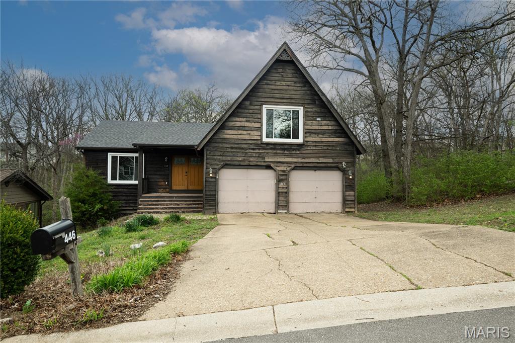 Welcome to this one-of-a-kind rustic retreat in the desirable Oak Hills subdivision of Lake St. Louis! This distinctive 4 bed, 2.5 bath home showcases a unique split-bedroom floor plan with incredible architectural character throughout. The stunning two-story great room features exposed wood beams, a wall of windows, and a cozy wood-burning fireplace, creating a warm and inviting atmosphere. The kitchen offers 42” custom cabinetry, custom tile backsplash, two pantries, and a bright breakfast room, all highlighted by real hardwood floors and beautiful Bavarian limestone flooring throughout.
Upstairs, the private primary suite impresses with soaring 16’ ceilings, a walk-in closet, and a recently remodeled en suite bath complete with a separate soaking tub and shower. A cozy loft area overlooks the main living space, perfect for a reading nook or home office. The lower level includes three additional bedrooms, a full bath, and a second wood-burning fireplace—ideal for guests or additional living space.
Additional features include a large laundry room with utility sink and private side entry, cedar siding, covered front porch, and a 2-car attached garage. Roof replaced in 2022. This home offers incredible potential and is ready for your personal touch, including deck replacement. Don’t miss the opportunity to make this truly unique property your own!