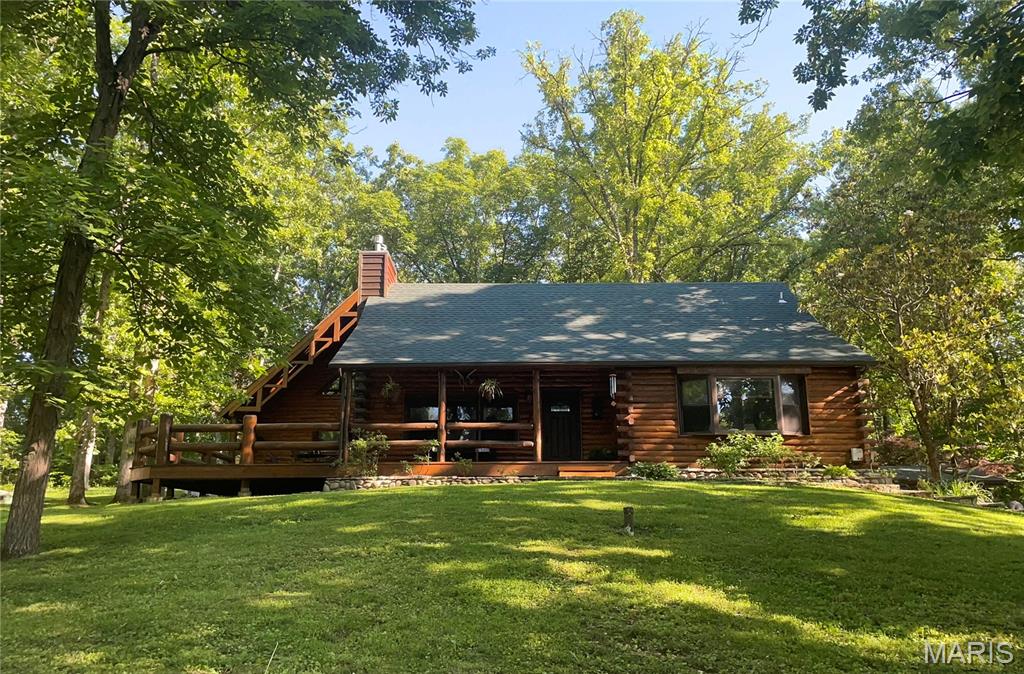 YOUR OWN PERSONAL LAKE LIFE RETREAT! Home on 2+ acres including Lake Lot at Lake Tishomingo  This meticulously maintained home is ONE OF A KIND, admired, filled with character, love and features that you can't find in most homes.  The newest addition with 1000 sq ft has it's own private entrance but also connects to the other side with a large foyer which provides you with 2 living quarters that you can use as the your Primary bedroom or in-law quarters with private ensuite, kitchenette, living room, dining and a gracious loft for additional sleeping for guests that the current homeowners call the Tree House due to the custom staircase that was designed and installed by a local artist. This custom log cabin is in the perfect setting with a lake front lot directly across the road and ready for you to design and install your own boat dock with a shed to store your fishing gear. Plenty of places to Entertain and gather on the 22x16 covered front porch, connecting to the 32x17 side deck with massive log rails. There is a wrap around patio that leads to the back of the house that enters into another extra large space that would be great for grilling, cookouts or a firepit seating area for all your guests to hangout. Easy to pull right up to it and unload groceries.  Plenty of parking for guests-2 driveways-gravel one in back and a nice long concrete driveway in front leading to the garage and portico to park under. Soaring vaulted ceiling in the Great Room and tongue and grove through out the rest of the house with a stone masonry wood burning fireplace and massive log mantle, custom built in bookcase, open staircases going up to your own private bedroom retreat with ensuite bathroom or head down to the finished walk out lower level that makes a great game room or home office.  The tuck under garage has a new epoxy floor and has ample storage and closets to keep everything organized.  Large eat in kitchen with thick wood ceiling beams, custom chandelier and plenty of natural light with the big picture window to gaze out at the lake while sipping your morning coffee. Features: durable flooring wood and ceramic throughout and 2 additional gas masonry fireplaces. New roof 2025, gutters & leaf guards, deck stained 2025, entire home stained/sealed in 2024 and new entry door. Lake amenities: picnic areas with tables, grills, swimming beach for sunbathing and water activities, Volleyball, basketball, playground. Hiking trails offering beautiful views and nature exploration. Fishing spots with opportunities for catching various species: bass, crappie, blue gill, channel cat, and perch. Boat ramps for easy access to watercraft and recreational boating.