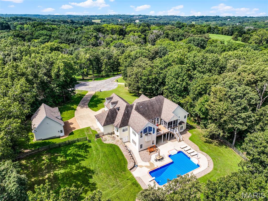 Nestled in a Peaceful Hollow, this expansive European ranch boasts privacy, luxury, & convenience.  Just minutes to Washington, this prestigious & revered subdivision features just 4 Lots, all with 5 acres. This sprawling Ranch Home offers luxurious design & features like Great Natural Light with Low-E Anderson Windows throughout both levels, which total 5200sqft of total living area. The Foyer open to the Office, Living Room, & Stairwell to lower level. Down from the Foyer, the HUGE primary Bedroom Suite features access to covered porch, walk-in closet with laundry, & sweet bathroom with shower, jetted tub, & two vanities. Extra main floor bedroom offers en suite bath as well. Living Room with pillars could serve many purposes as it leads to the deck, foyer, & kitchen. Luxury Kitchen offers Island, Thermador Appliances like cafe-style oven & access to Hearth Room & Dining Area with Pantry. Main Hall connects open Living space with Mud Room & 3-car attached garage. Lower level offers sprawling entertainment from the large Game Area to Bar Area with Wine Cooler to the Family Room with surround sound. Down the hall, 2 large bedrooms offer walk-in closets & shared jack-&-jill bathroom, plus a Craft Room. LL Bathroom can be accessed from Game Area & patio to pool area.  Oops, almost forgot to mention the POOL!! What about a detached garage with Loft, a fenced yard enclosed by trees, or Smart Features!? Lucky For YOU, these are included, which make this a true 'MUST SEE PROPERTY'!
