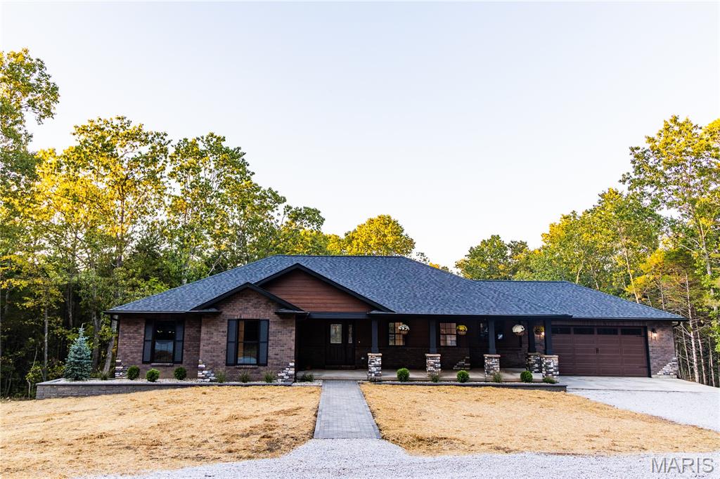Welcome home to this stunning custom-built ranch, perfectly nestled among majestic pine and oak trees on 6.2 peaceful acres in a private subdivision. Thoughtfully designed and quality built from top to bottom, this home blends beautifully into its natural surroundings. The exterior showcases a welcoming mix of queen-sized brick, stone piers with corner waterfalls, and premium LP wood siding with a 30-year Diamond Kote finish. Beautiful landscaping and a paver walkway lead to the spacious covered front porch that sets the tone for what’s inside.  Step through the beautiful wood grain front door and into an open, light-filled interior featuring gorgous wood floors, a striking stone gas fireplace, and vaulted ceilings in the great room and primary bedroom.  The kitchen impresses with Category E granite countertops, custom KraftMaid cabinets featuring "lazy Susans", matching Fridgedaire dark stainless appliances and quality finishes throughout. The large Fiberon composite deck is a perfect place to enjoy nature while the sipping your favorite beverage.  Convenient main-floor laundry adds everyday ease. Both bathrooms feature LED mirrors and the primary has dual vanities & accent lighting for a spa-like touch.  Built for comfort and accessibility, this home includes Knotty Alder solid 36" doors throughout.  The walk-out lower level offers endless possibilities with a 9’ pour, 2 egress windows and a rough-in for a full bath ready for additional bedrooms or whatever your lifestyle requires.  Other quality features include Anderson windows, blown-in blanket insulation, a high-efficiency heat pump HVAC system, and Landmark Pro architectural shingles, eggshell paint finish throughout and much more.  The 24' x 24' insulated garage easily accommodates most trucks and SUVs.  As owners of this gorgeous home you have access to a beautiful 86-acre lake—perfect for fishing, kayaking, or simply relaxing by the water. This exceptional property is a rare find that combines craftsmanship, comfort, and the beauty of country living. Truly a must-see!