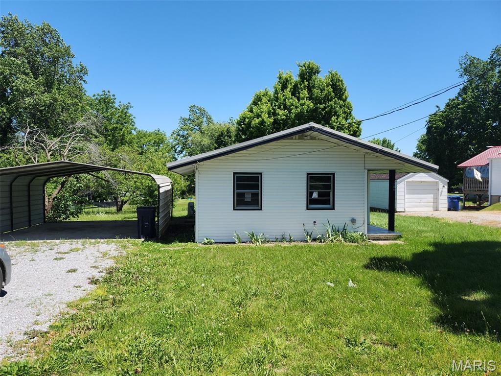 This single-story, ranch-style home, constructed in 1950, features vinyl siding and offers 960 square feet of interior living space. The layout includes two bedrooms and one full bathroom, all located on the main level. Mechanical systems include an electric cooling system and forced-air heating.  The property is situated on a 0.34-acre lot with front and back yards. Exterior amenities include a detached, two-car carport for covered vehicle parking.