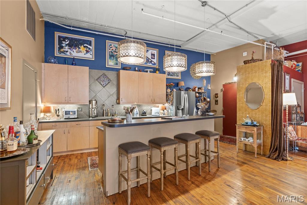 Soaring ceilings with exposed ductwork combined with the dramatic brick accent wall form a true loft-style atmosphere where you find spacious living, timeless loft charm, and abundant natural light. 

Open to the Chef’s Kitchen with Bold Character & Entertaining Appeal.  The spacious central island is at the heart of the home and a natural gathering place.  This kitchen isn’t just functional — it’s a true showstopper that invites gathering. Whether you’re a serious home cook or love entertaining, this space delivers both everyday practicality and wow-factor appeal. A rare combination of warmth, personality, and versatility.  

The primary bedroom is spacious and serene, bathed in abundant natural light.  It offers a peaceful retreat while maintaining the vibrant spunk and creative energy that is found throughout this home.  

The second bedroom is currently functioning beautifully as a library, office, and guest space.  This flexible room adds energy and personality while the abundant shelving keeps everything beautifully organized.  

There is even a private balcony with beautiful city views.  At the top of the building, there is also a rooftop terrace with stunning city skyline views. 

The homeowners' association dues include a dedicated underground assigned parking spot (immensely helpful!) Designated parking is  convenient and provides security.  Truly PRICELESS!  For even more added security, there is a video intercom system for guests.  The HOA fee also includes 5G Internet, trash, water, sewer, heating, recycling, and a dedicated storage unit. 

This is a sophisticated, secure loft community to call home.