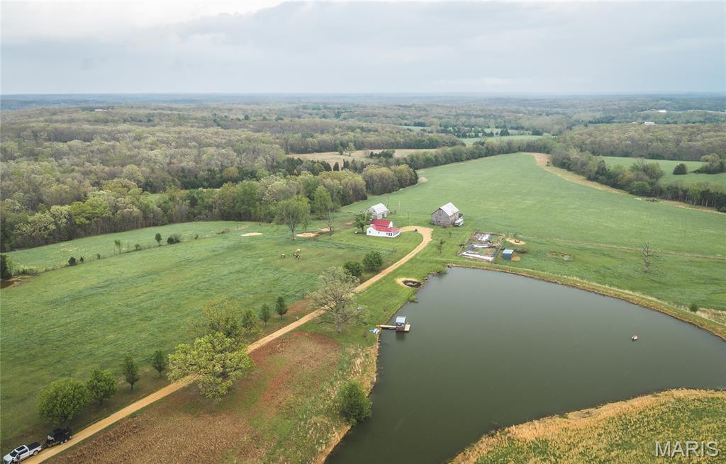 Set in the rolling countryside of Gasconade County, Quail Ridge Acres offers 160 +/- acres of well-balanced ground combining open pasture, mature timber, and multiple water features, all anchored by a classic white 2-story farmhouse. The 3 bedroom, 1 bath farmhouse offers approximately 1,600 +/- sqft and reflects a traditional design with thoughtful updates over time. The home features an updated kitchen, comfortable living spaces, and a sunroom overlooking the lake, creating a natural connection between the home and the land. Positioned to take advantage of the setting, the home overlooks a stocked 2-acre lake, with views extending across the surrounding acreage. Approximately 100 acres of the property is open and currently utilized for hay and recreation, with the remaining acreage in woods providing an excellent wildlife habitat with abundant turkey and deer. The farm has been thoughtfully improved by the current owners and is  now set up for quail management, bird dog training, and horseback riding, with established trails running throughout the property. In addition to the main lake, the property includes two smaller ponds and a wet weather creek, enhancing both usability and wildlife appeal. Improvements include a well-maintained barn with horse stalls along with an additional outbuilding suited for equipment, livestock, or recreational use. Quail Ridge Acres is an opportunity for those seeking a private, well-rounded farm offering both a comfortable home and exceptional recreational ground.