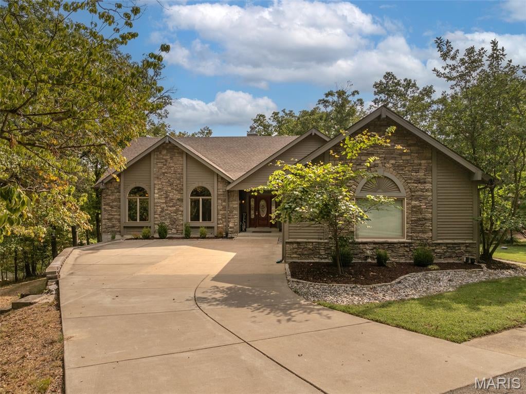 Lakefront living at its best at Innsbrook Resort! Set along the water with beautiful lake and golf course views, 513 Woodlake View Dr. offers the space, setting, and amenities to enjoy as a full-time residence or a relaxing second home. With four bedrooms, three full baths, incredible indoor and outdoor entertaining spaces, and a private dock, this is a home designed for enjoying everything Innsbrook has to offer. Step inside and the first thing you'll notice is the sense of space. The vaulted living room and kitchen create an open, inviting gathering area, while walls of windows bring in an abundance of natural light and showcase the surrounding woods and lake. A stone fireplace with a beautiful mantle anchors the living room and is flanked by built-ins. The spacious kitchen features a large island, breakfast bar, double ovens, plenty of cabinetry, and a pantry. All appliances are included. Just beyond the kitchen is a generous dining area along with a separate sitting room that provides a comfortable spot to relax, read, or enjoy the views. The main level includes three bedrooms, including a spacious primary suite with wonderful lake views, a large closet, and a private bath featuring a separate tub and shower. 
Step outside onto the deck where the views really take center stage. Enjoy your morning coffee overlooking the lake and golf course or gather with friends and family for dinner as the sun goes down. And then there's the finished lower level. This is where the fun really begins. A huge bar is ready for serving drinks and refreshments, with multiple dining areas providing plenty of room for entertaining. The large TV lounge offers a comfortable place to gather and features a second fireplace. More windows and doors fill the space with natural light. The lower-level bedroom is truly massive and offers plenty of flexibility. In addition to serving as a fourth bedroom, it could easily accommodate a recreation room, home office, bunk room, exercise space, or whatever best fits your needs. Walk outside from the lower level and you'll find an expansive patio leading down to your private firepit and dock. From here, take in the peaceful lake views with the golf course stretching out in the distance. But the best feature might be something you don't see at all. Listen closely and you'll hear the soothing sound of your own babbling brook. A recirculating stream from the lake creates a wonderfully relaxing backdrop as you enjoy lake life. When it's time to get out on the water, you're conveniently located near the boat launch on Lake Aspen for easy pontoon access. The Innsbrook golf course and clubhouse are also nearby. The home is being offered mostly furnished, with some exclusions, making the transition to Innsbrook living even easier. Whether you're looking for a primary residence or a weekend retreat, 513 Woodlake View Dr. delivers!