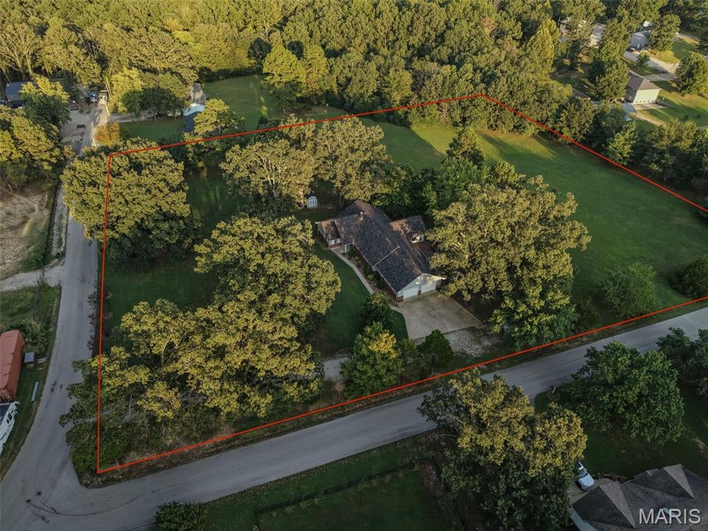 114 County Road 4221, Poplar Bluff, MO- Situated in a desirable location north of town on a paved road, this well cared-for residence offers over 3,000 square feet of comfortable living space set on a fantastic 3+ acre level lot. Frame-worthy views of mature shade trees and local wildlife create a peaceful, park-like backdrop with a large yard perfect for outdoor recreation and gathering. Inside, you will find generous room sizes with ample closet storage, a formal living room, a formal dining room, and a cozy family room right off the kitchen. The home's true centerpiece is the rear sitting room, showcasing vaulted ceilings and a wall of windows that treat the space with natural light while framing relaxing views of the shaded backyard. Complete with 3 bedrooms, 2 bathrooms, and a spacious back deck ideal for entertaining, this exceptional property blends rural tranquility with effortless proximity to town amenities. Well water. Auxiliary wood stove. Oak Grove School district.