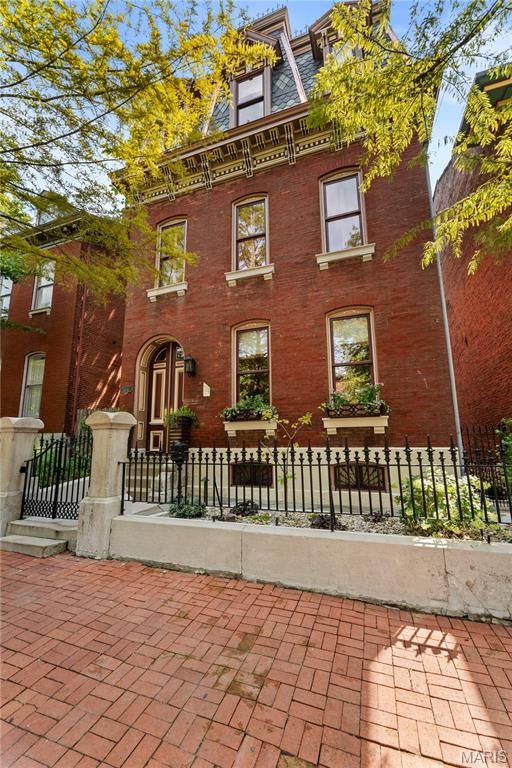 Built circa 1869 and rooted in more than 150 years of St. Louis history, 1840 South 8th Street is a remarkable Soulard residence where the architecture tells a story all its own. Historical research traces the home to German born bricklayer and stonemason Charles Eyermann, with later two story additions made during the ownership of prominent commission merchant Julius Petersen. The property has evolved through generations while retaining the craftsmanship and character that make historic Soulard homes so distinctive. Extensive whole house renovations have been completed inside and out with particular attention paid to preserving the architectural integrity of the residence. Exterior improvements include intricate mansard shingles and gutters thoughtfully executed to remain consistent with the home’s historic architecture, while comprehensive interior renovations allow the house to function beautifully for modern living without sacrificing the details that give it its identity. Inside, original wood floors, substantial millwork, exposed brick, soaring ceilings and an extraordinary carved stone fireplace create a dramatic backdrop for a home that is anything but ordinary. Rich color, statement lighting and thoughtfully selected finishes bring a sophisticated, collected sensibility to the historic interiors. The expansive living and dining spaces flow together beautifully, equally suited to entertaining a crowd or enjoying the intimacy of the home’s architectural details. The kitchen offers an unexpected amount of space for a home of this vintage, with extensive cabinetry, stone countertops, a large center island with seating, stainless appliances, abundant storage and a casual dining area surrounded by natural light. Original wood floors continue throughout, while the adjoining staircase, period trim and preserved architectural elements provide a constant connection to the home’s past. Perhaps most compelling is the juxtaposition of old and new. Ornate millwork meets contemporary art. Exposed brick sits alongside jewel toned walls. Historic woodwork, distinctive lighting and modern furnishings give the interiors a personality rarely found in a conventional renovation. Even the hallways have been treated as architectural moments, with dramatic wallcoverings, custom lighting and carefully preserved trim. The documented history of 1840 South 8th stretches from its likely construction around 1869 through generations of owners and uses, including more than five decades associated with the Petersen family. The historical record also documents two story additions dating to the 1880s, adding another layer to the story of a residence that has continually adapted while remaining unmistakably connected to its origins. This is not a reproduction of historic St. Louis. It is the real thing. Meticulously renovated, architecturally significant and unmistakably individual, 1840 South 8th offers the increasingly rare opportunity to own a piece of Soulard history that has been carefully stewarded for its next chapter.