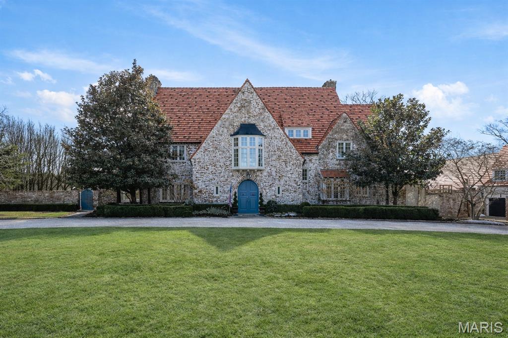 Set along one of Ladue’s most exclusive and private lanes, this truly unique estate is a rare architectural offering, evoking the charm of the English countryside. A discreet circular drive creates a gracious arrival, highlighting the inviting facade of whitewashed brick, classic tile roof, and timeless detailing—an elegant expression of the enduring design of one of St. Louis’s preeminent early 20th century architects, and an introduction that immediately sets this home apart. Inside, a dramatic two-story entry with slate floors sets the tone for interiors that balance grand scale with warmth and livability. The expansive paneled living room is perfectly suited for both everyday enjoyment and memorable holiday gatherings. A light-filled sunroom opens seamlessly to the extraordinary grounds beyond, where an expansive, flat lot is framed by mature trees and complete privacy, anchored by a bluestone patio, serene saltwater pool, and dedicated pool bath—an ideal setting for outdoor entertaining or quiet retreat. The dining room stuns with fresh lacquered walls and a striking marble mantel, flowing effortlessly into the chef’s kitchen with marble countertops, custom cabinetry, and an inviting eat-in space. A well appointed bar connects to the vaulted family room, where a cozy fireplace creates the perfect gathering place. The main house offers six bedrooms, including a luxurious primary suite with a spa-like bath featuring heated floors, steam shower, double vanities, and an expansive walk-in closet. Two oversized ensuite bedrooms occupy the second floor, while the third floor includes three additional bedrooms sharing a beautiful hall bath. The lower level is designed for both leisure and wellness, complete with a temperature-controlled wine room, recreation space, exercise area, sauna, and steam room. A heated four-car garage is topped by a spacious apartment offering flexible living space, bedroom, full bath, and kitchenette—ideal for guests, extended family, or private work-from-home needs. Geothermal heating and cooling add efficiency to this remarkable estate. Properties of this caliber are seldom available, and this residence has not been offered to the public market in many years, having changed hands quietly—making this opportunity all the more special. Rich in character, rare in availability, and endlessly inviting, this is a truly special residence that feels both storied and timeless.