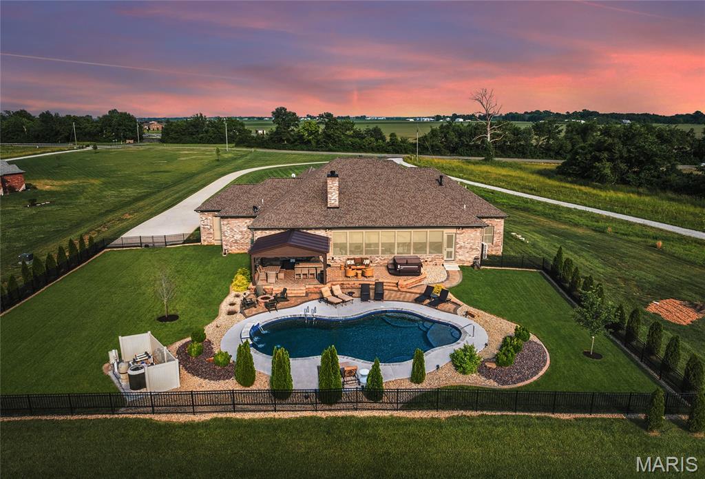 Coming soon on 8JUL.  Custom-built retreat in award winning Edwardsville schools blends modern sophistication with quiet country charm. Situated on a private 5 Acre lot that backs up to trees & the MCT bike trail!  Enjoy sunrises and sunsets from the enclosed patio, or relax by the heated gunite pool w/waterfalls, cool-crete decking, surround sound, & outdoor gas firepit. Entertain under the covered patio with a luxurious outdoor outdoor kitchen.  No carpet in this masterpiece, only real hardwood & tile flooring throughout.  Gourmet kitchen opens to the great room & enclosed patio.  It features custom Amish cabinetry, high end stainless appliances, incl. double oven & gas cooktop with built in hood.  Large center island made for entertaining & walk in pantry.   Home has such a grand & open feel with 10' high ceilings & 8' tall solid core doors.  Unique touches like an oversize swing in the enclosed patio, dedicated Christmas tree closet, & access to laundry from walk in closets, add personality & functionality. Spacious master suite (20x21) also connects to enclosed patio.  Geothermal HVAC, dual tankless water heaters, EV car outlet, irrigation system, plantation shutters, & smart security system with window/door sensors, smoke & sump pump monitoring. Paved driveway leads to an oversized 4-car garage. Wired for a dog fence, backs to bike trails, & minutes from the interstate & downtown Edwardsville—this home offers the tranquility of country living with access to everything!