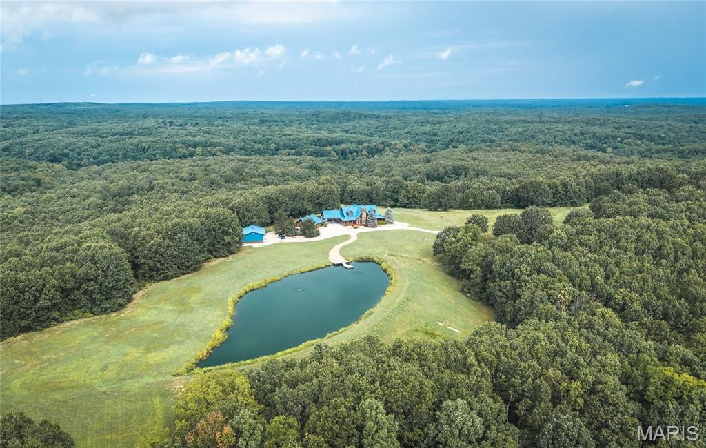 Discover Oak Ridge Ranch, an exceptional 196-acre estate in Morgan County just minutes from the Lake of the Ozarks. This private property offers the perfect combination of luxury living, recreation, hunting, and agricultural opportunity. The log home features 4 bedrooms, 5 bathrooms, a loft, full basement, high-end finishes, Pella windows, wood floors, screened deck, heated in-ground pool, and custom landscaping. The home is fully furnished and designed for entertaining. Outdoor amenities include a beautiful stocked pond with bass, bluegill, and catfish, aerator, dock, trails throughout the property, wet-weather creeks, mature timber, multiple ridgelines, lush pasture, and excellent deer and turkey habitat. The fenced acreage offers opportunities for livestock or hay production, with multiple entry and exit points for convenient access. Additional improvements include two garages, carport, metal roof, secure electric gate, automatic generator, 400-amp service, extensive security camera system, alarm system, and concrete safe room. The property is offered as a turnkey retreat with furnishings and an impressive equipment package, including a John Deere 4500 4WD tractor with attachments, zero-turn mower, Polaris Ranger 4x4, wood chipper, brush hog, pressure washer, air compressor, fishing equipment, paddle boat, and more. A 24-foot deck boat with lift is also included.