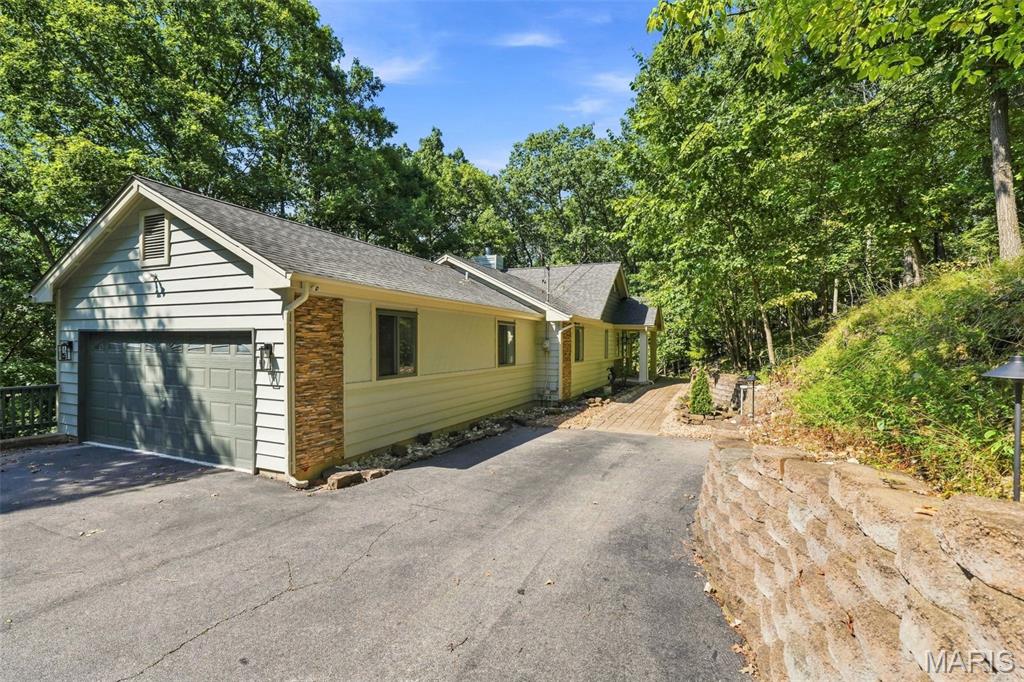 Welcome to this rustic oasis nestled among the picturesque landscapes of Wildwood. 
Set on approximately three wooded acres, this spacious home combines modern updates with the tranquility of your own private retreat. 
The inviting living room features a wood-burning fireplace with custom fireplace doors installed in 2022, while the separate dining room provides an ideal setting for entertaining. Tasteful updates throughout the home include beautifully renovated kitchen cabinetry, quartz countertops, backsplash, ceramic farmhouse sink, updated faucet, stainless steel appliances, and new flooring. 
The main level also offers a conveniently updated powder room and laundry room with tile flooring. The primary suite provides a peaceful escape, featuring updated cabinetry, a separate shower, and an air-jet soaking tub. New lighting fixtures and ceiling fans have been installed throughout the home, and four generously sized bedrooms offer plenty of space for family and guests. 
The finished lower level includes a spacious recreation room with access to a deck overlooking the serene wooded surroundings. Additional lower-level features include two storage areas and a 75-gallon water heater. 
The garage is equipped with a 50-amp outlet and a professionally resurfaced floor backed by a transferable warranty. 
A rare opportunity to enjoy privacy, nature, and modern comfort in one of Wildwood's most desirable settings. Move-in before the Holidays!