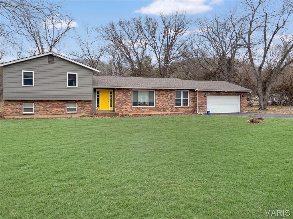 This remarkable home on nearly one acre in House Springs has 4-bedrooms, 3-baths, 2-car garage (depth of home) that is updated with beautiful. The entry has real wood flooring and opens to the oversized living room with newer, oversized windows, and to the attached, raised dining room with real wood flooring. Next is the hearth room with a wood-burning fireplace, walk-out to a patio area, and the newer kitchen, freshly painted with granite countertops and modern cabinetry, beautiful marble-style ceramic flooring, greenhouse window. The kitchen also has tons of storage, stainless steel appliances, and a breakfast bar. The main floor laundry is off the kitchen, and there is an additional laundry room in the lower level. The primary bedroom is spacious and has its own private, walk-out to a balcony. The beautiful primary bath has an oversized, walk-in glass shower + a large soaking tub, modern fixtures and cabinetry. There are 3 other bedrooms that are large & have walk-in closets. The hall bath was remodeled with new cabinetry, lighting, and new flooring. Travel to the recreation room on the lower level, which would be a great media room. There is also the 4th bedroom, an additional laundry room with a walk-in closet for storage, and a utility room. The lot is large (.93 acre) is level and has privacy in the back yard. The oversized 2-car garage has ample space for storage, lawn equipment, and more. The open yard has some trees, a playground area, a private patio, and is on a corner lot. Don't miss this opportunity! Home is being sold as-is which is no reflection of its condition.