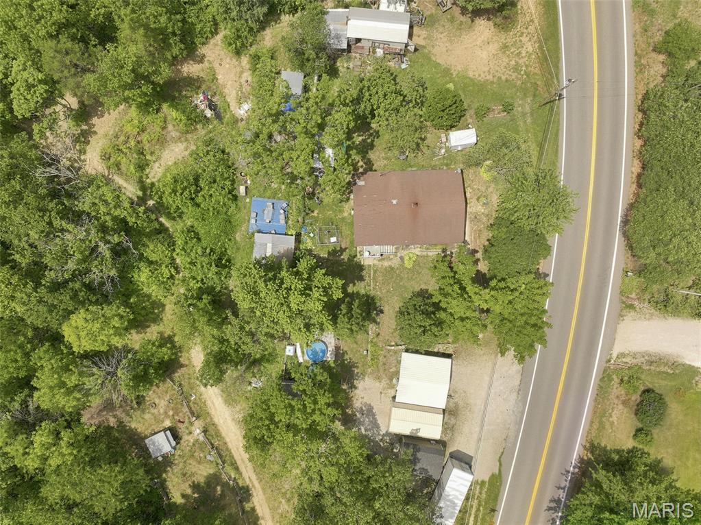 The potential here is endless! 14 stunning acres right off of Highway H. Design your own country oasis, split the lot up for development and keep the existing home as a rental, or live in the existing home while you build your dream home! 2-car carport, 3 sheds, a workshop with electric, and a garage with electric all stay with the sale. Roughly 10 acres of the property is fenced per the owner.  The home features 2 beds and 1 bath with separate kitchen and dinning as well as main floor designated laundry area. Living room has beautiful raw wood beam accents. Kitchen has custom hand made solid wood cabinets with many neat features, a double bowl sink, and tiled counter tops. Electric stove is 2 years old with a microwave/ vent mounted above. Stainless steel Refrigerator stays with the sale of the home. Central HVAC is 6 years young. Heat is functioning. AC components are there but were never hooked up per the owner. Currently has window units for AC which stay with the sale of the home. Home also has a DAKA forced-air wood and coal furnace. Hot water heater is 6 years old per the owner. basement is the perfect space for additional storage. Access from exterior only. Well head was replaced in the last 6 years as well per the owner. 

Exterior covered patio area has a natural stone floor and fish pond that also adjoins a large 12X12 deck area. Perfect for outdoor entertaining. 

This home has so much potential and the property is just gorgeous! Don't miss your chance to own your very own slice of heaven. Bring your sweat and enjoy the equity!