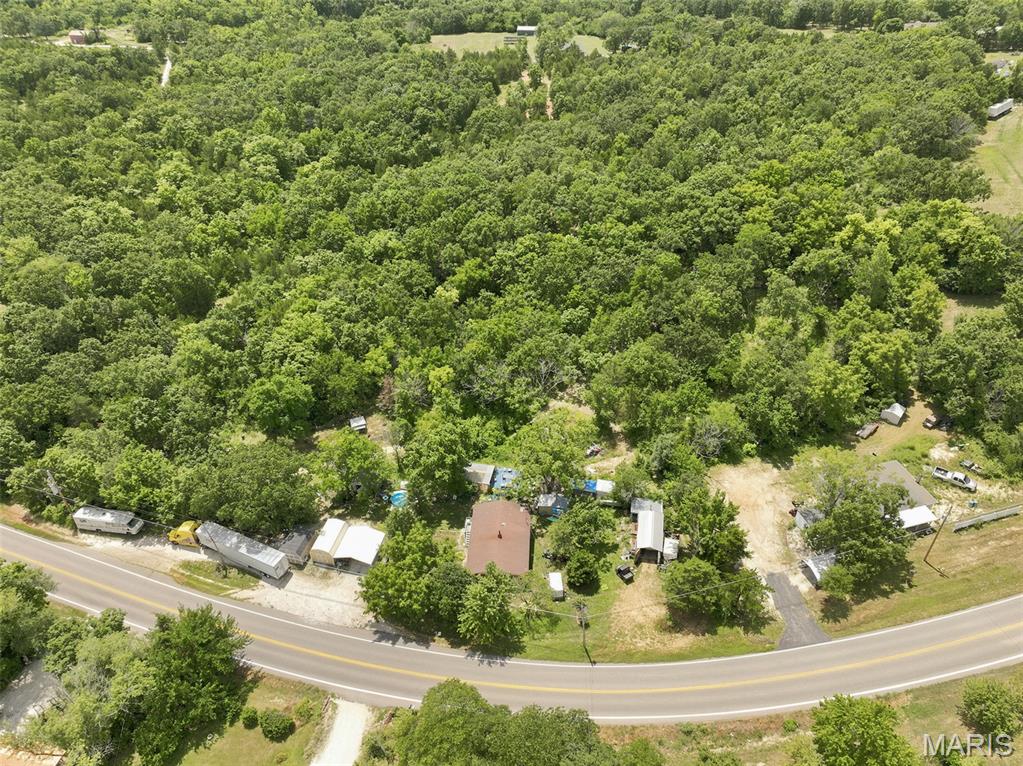 The potential here is endless! This is a cash or private financing (NO OWNER FINANCING) only As is sale. No conventional loans will be accepted. 14 stunning acres right off of Highway H. Design your own country oasis, split the lot up for development and keep the existing home as a rental, or live in the existing home while you build your dream home! 2-car carport, 3 sheds, a workshop with electric, and a garage with electric all stay with the sale. Roughly 10 acres of the property is fenced per the owner.  The home features 2 beds and 1 bath with separate kitchen and dinning as well as main floor designated laundry area. Living room has beautiful raw wood beam accents. Kitchen has custom hand made solid wood cabinets with many neat features, a double bowl sink, and tiled counter tops. Electric stove is 2 years old with a microwave/ vent mounted above. Stainless steel Refrigerator stays with the sale of the home. Central HVAC is 6 years young. Heat is functioning. AC components are there but were never hooked up per the owner. Currently has window units for AC which stay with the sale of the home. Home also has a DAKA forced-air wood and coal furnace. Hot water heater is 6 years old per the owner. basement is the perfect space for additional storage. Access from exterior only. Well head was replaced in the last 6 years as well per the owner. 

Exterior covered patio area has a natural stone floor and fish pond that also adjoins a large 12X12 deck area. Perfect for outdoor entertaining. 

This home has so much potential and the property is just gorgeous! Don't miss your chance to own your very own slice of heaven. Bring your sweat and enjoy the equity!