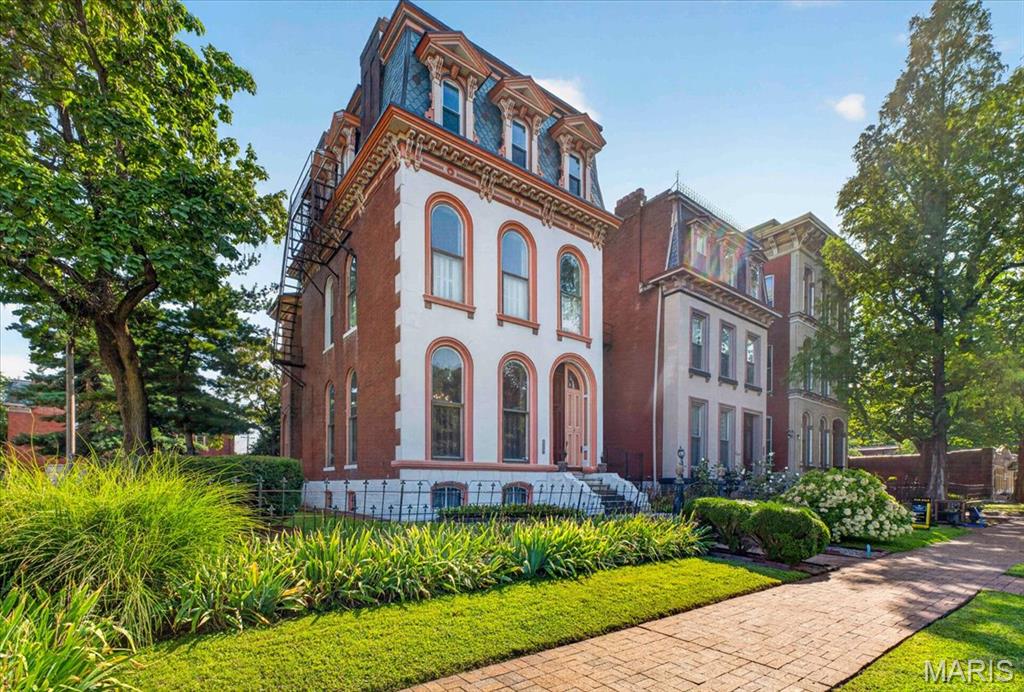 NEW PRICE! Built in 1880, this home is remarkable and one of the largest examples of Second Empire architecture found in Historic Lafayette Square. Very well maintained and cared for, this home is ready for it's new owners. It's flared mansard roof, and classic pediments over rounded dormer windows give it amazing presence. Unlike many older homes, unique architectural features remain inside as well. For example, large plaster moldings, ceiling medallions, and the original staircase that runs continuously all 3 floors are just a few. Another is the very large double parlor, with almost floor to ceiling round top windows at the front and sides, still with original pocket shutters keeping the room bright. Additionally, you will find two matching marble mantled fireplaces. There are a total of 5 beautiful fireplaces within the property. Because it's located on an extra large lot, both in width and depth, the home is the rare 4 rooms deep, style of home, that has allowed for a family room off the modern renovated kitchen, a modern large half bath, and rear hallway area with coat closet. The beautiful kitchen has tons of custom cabinetry, acres of granite counters, center island and farmhouse style sink, and Viking appliances. The use of tile and exposed brick make keep it warm. There is a drop zone by the back door and an open rear staircase flows up from the kitchen. Out the back door is a covered porch. The 2nd floor has 3 generous sized bedrooms all with closets, another family room, and two full baths, both renovated. The third floor has another fully renovated bath and two additional bedrooms, the front being used as a hangout gaming lounge for a teen. There is a full basement with walk out. The front of the property greets you with a gated wrought iron fence and outer double doors conceal the front doors. A wide side yard has privacy fencing and gate leading to the enormous back yard where you will find a large brick patio, surrounded by landscaping and a covered BBQ Grille shed with a small bar. At the rear of the property is a large 2 car garage and a large generous parking pad which will hold 2 large SUVS. Located directly across from Lafayette Park, you are at the center of the Square. Host Gateway Bike race parties in your front yard, enjoy the Concerts in the Park from you front yard, you are steps away from so much to see and do. This is Lafayette Square living on a grand scale! Won't you start the next chapter in the history of this notable property.