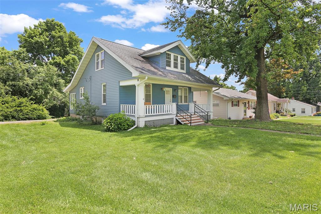 Charming 1.5-story home full of character and opportunity! A spacious covered front porch provides the perfect place to relax or gather with family and friends. Situated on a corner lot, this home offers nearly 1,400 square feet of living space, four bedrooms, and a detached one-car garage. Rich in timeless character, you'll appreciate the beautiful original woodwork, charming arched doorways, built-in dining room cabinetry, and abundant natural light throughout. The spacious main level features a large living room, formal dining room, generously sized kitchen with abundant cabinetry, a bright enclosed sunroom just off the kitchen, bathroom, and a main-floor bedroom with a full wall of double closets. Upstairs, you'll find three additional bedrooms, offering flexibility for family, guests, or a home office. The seller will provide a one-year home warranty, and the home has already passed the Collinsville municipal occupancy inspection. Home is being sold AS IS. With its classic charm, generous living space, and endless potential, this is a wonderful opportunity to make this home your own.