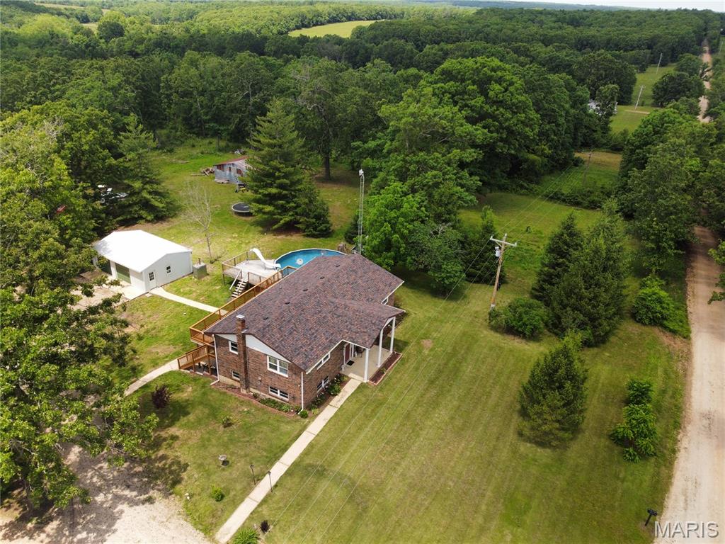 Looking for acreage, privacy, and plenty of space both inside and out? This 5-bedroom, 2-bath home sits on approximately 16 acres while still offering convenient access to town, Oak Hills Country Club, shopping, and everyday amenities. The property features two ponds, a barn, wet-weather creek, year-round creek along the back portion of the property, established trails suitable for a golf cart, fruit trees, an abundance of wildflowers, and frequent wildlife sightings. Bee hives are currently located on the property. A standout feature is the insulated 20x30 shop with heat and air conditioning, an independent electrical panel, and 220V and 110V service, offering a great setup for a workshop, hobbies, equipment, or additional storage. The home offers multiple heating options, including electric HVAC and a Hardy outdoor wood furnace. A Fire Chief wood-burning system is also present with the potential to be connected for use in the living room. The lagoon has been updated and expanded. Outdoor living is another highlight with a full-length deck leading to a newer, professionally installed 32-foot round above-ground pool complete with a water slide. With acreage, water features, trails, outbuildings, recreational space, and a secluded setting close to town, this property offers a combination that can be hard to find. Inside, updates include lower-level flooring, fresh paint, updated appliances, and additional improvements throughout. With five bedrooms, multiple gathering spaces, and approximately 16 acres to enjoy, there is plenty of room to make this property your own.