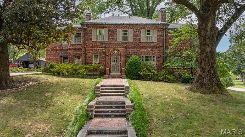STEP INTO TIMELESS SOPHISTICATION with this classic two-story Georgian style brick home, perfectly situated on a beautifully landscaped corner lot. Showcasing the architectural integrity of its era, this 1936 home boasts beautiful crown molding, an ornate wood framed fireplace, and pristine original hardwood floors. The formal foyer features high ceilings and a sweeping central staircase, setting the tone for the character found throughout the home. The updated kitchen features granite countertops, a double oven, and Viking and KitchenAid appliances. A wood-planked study and all-seasons room add to the home’s charm and versatility, while a beautiful sitting room features handcrafted coffered wood ceilings and panoramic windows. Generously sized bedrooms offer versatility and abundant closet space. Outside, the manicured back courtyard provides a beautiful setting for relaxing or entertaining. The property also includes a tuck-under two-car garage plus an additional detached two-car garage, offering plenty of parking and storage. A new roof in 2024 adds to the list of recent improvements, creating a home that beautifully balances its original character with thoughtful updates.