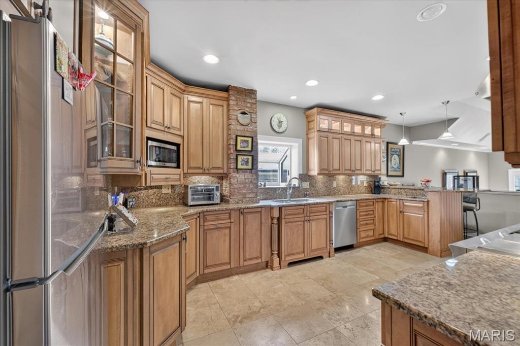 The home's main-level focal point is a large, updated, eat-in kitchen off the large and inviting entry foyer, featuring an antique chandelier. The chef's kitchen features plenty of honey-maple cabinetry, all stainless-steel appliances, and breakfast counter. The large and inviting Primary bedroom features a bay window with a view of the backyard along with a window facing the side yard.  There is a wide mini-hallway that features a walk-in closet, leading to the ensuite, remodeled bathroom with double vanity and double, walk-in shower. The junior suite also features an elongated contiguous dressing area with closets and entry into the full bathroom. The Great Room and adjoining dining area features wide, step downs from the main entry, kitchen and bedroom hallway; two full-glass doors leading to the attached wood deck and expansive yard; there is also an oversize, glass door fireplace, 11' mansard ceiling all on well cared for, hardwood flooring.  This home's open floor plan and large wood-burning fireplace makes this home inviting for either a cold winter night or holiday entertaining with a house-full of guests.  This home is a unique find in the heart of one of St. Louis County's most desired locations.