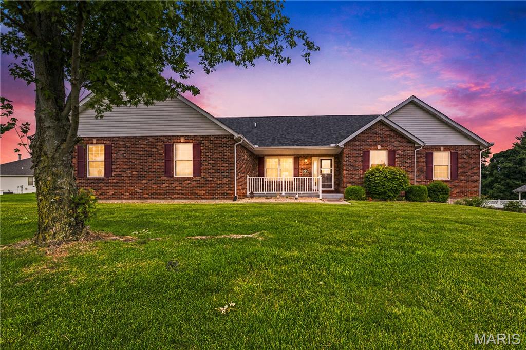 Welcome to 818 E Wood Drive, a beautifully maintained four-bedroom, three-bathroom ranch home in Columbia, Illinois, offering more than 2,000 square feet of living space on the main level. Built in 2002, this spacious brick-front residence features an attached garage, finished living space on two levels, a sunroom, workshop area, and inviting indoor and outdoor spaces designed for comfortable living and entertaining.

A covered front porch, attractive landscaping, and classic brick exterior create excellent curb appeal. Inside, abundant natural light, vaulted ceilings, and gleaming hardwood floors contribute to the home’s open and welcoming atmosphere. The formal dining room provides an ideal setting for holidays and gatherings, while the spacious great room offers plenty of room to relax or entertain.

The well-designed kitchen features generous wood cabinetry, extensive counter space, a tiled backsplash, stainless steel refrigerator, and a large peninsula offering additional workspace and casual seating. An adjoining dining area keeps the kitchen connected to the main living spaces. The bright, window-filled sunroom is a standout feature, with a vaulted ceiling and views of the surrounding property—perfect for morning coffee, reading, relaxing, or entertaining guests.

The generously sized primary bedroom features a vaulted ceiling, hardwood flooring, and ample space for additional furniture. The private primary bathroom includes a double-bowl vanity, walk-in shower, soaking tub, updated flooring, and abundant storage. Three additional bedrooms and two additional bathrooms provide flexibility for family, guests, hobbies, or home-office space.

Additional features include convenient main-level laundry, a dedicated workshop area, plentiful storage, and an attached garage. Outside, enjoy the private backyard, patio, covered front porch, and expansive outdoor living areas with multiple places to relax or gather with friends. Thoughtfully maintained and filled with functional living space, this Columbia, IL ranch home offers four bedrooms, three bathrooms, a desirable layout, and exceptional versatility in beautiful Monroe County.