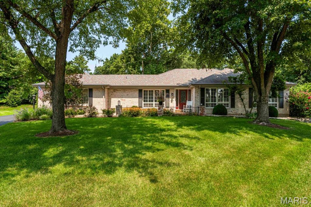 Distinguished all-brick ranch situated on a prime lot in the highly sought-after Claymont subdivision. Meticulously updated throughout, this residence seamlessly combines sophisticated indoor living with an extraordinary exterior designed for grand-scale entertaining. A stately covered front porch opens to an expansive foyer, flanked by an elegant formal dining room and a light-filled sitting room. At the heart of the home, the impressive family room features vaulted ceilings, a cozy gas fireplace with stone surround, and a built-in bar. Modern culinary convenience meets timeless style in the chef’s kitchen, outfitted with premium updated appliances, an expansive center island, and picturesque views leading into the serene four-seasons room. Three sets of glass sliding doors open to multiple impeccably landscaped stone patios, creating a fluid indoor-outdoor sanctuary. The primary suite serves as a luxurious retreat, featuring dual closets and a barn door leading to a updated en-suite bath. Two additional main-level bedrooms share a stylishly updated full bath. Rich hardwood flooring flows beneath carpeted areas, complemented by parquet flooring in the family room, custom plantation shutters, updated two-panel doors, and crisp neutral tones throughout. The versatile lower level expands your living space with a recreation room, a second bar area, a half bath, and dedicated space for a private home office or guest suite. Outdoors, the resort-style backyard boasts multi-tiered patio spaces, a newer retractable awning for shaded lounging, and an ambient gas fire pit perfect for crisp autumn evenings. Exceptional craftsmanship and timeless design make this home a rare offering.
