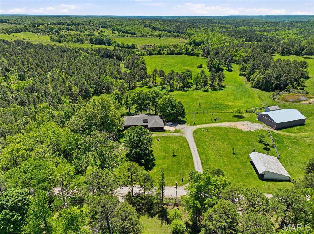 This 154+/- acre one family owned farm checks many of the boxes on your wish list. For a very brief moment your wheels come off of ashaplt and touch gravel but you will barely notice because the views are stunning! With minimal effort you can be working cattle, tending to horses or any of the farm animals you've been dreaming of. The holiday gatherings to be had in the spacious great room and sunroom will be treasured forever. Updating this 3bd/3ba house to be your home may be your preference but with this build quality your off to a great start.  The lower level offers more space for your family's perfect game room w/o sacrificing storage or that craft room/man cave you've dreamt of. In the  3000sf +/- barn there is a workshop and  2 double stalls. The Apple tree, grape arbor, and tame blackberries produce yearly. There are 2 ponds on the property. There are drivable trails around the fenced perimeter that borders 770 acres of U.S. Forestry land. This well maintained property has approx. 40 acres cleared and/or pasture land including a warm season grass field. One 3 sided outbuilding is well stocked with firewood, the other one is ready for your equipment. Roof was replaced in 2025 and AC unit in 2024. A Victor wood heat source & radiant ceiling heat to keep the pipes from freezing for any winter getaways. For efficiency the fireplace is ducted into the sunroom, primary bathroom & mud room. The wood box can be kept stocked from outside, even with an entire house has central vac, not having wood hauled through the house is a bonus. HIGH SPEED INTERNET provides opportunity to work from home or run your own business onsite. If you have been looking for a destination property for a specialty venue, THIS IS IT! Less than 2 miles from the Big Piney River. Properties that offer so very much don't hit the market too often.