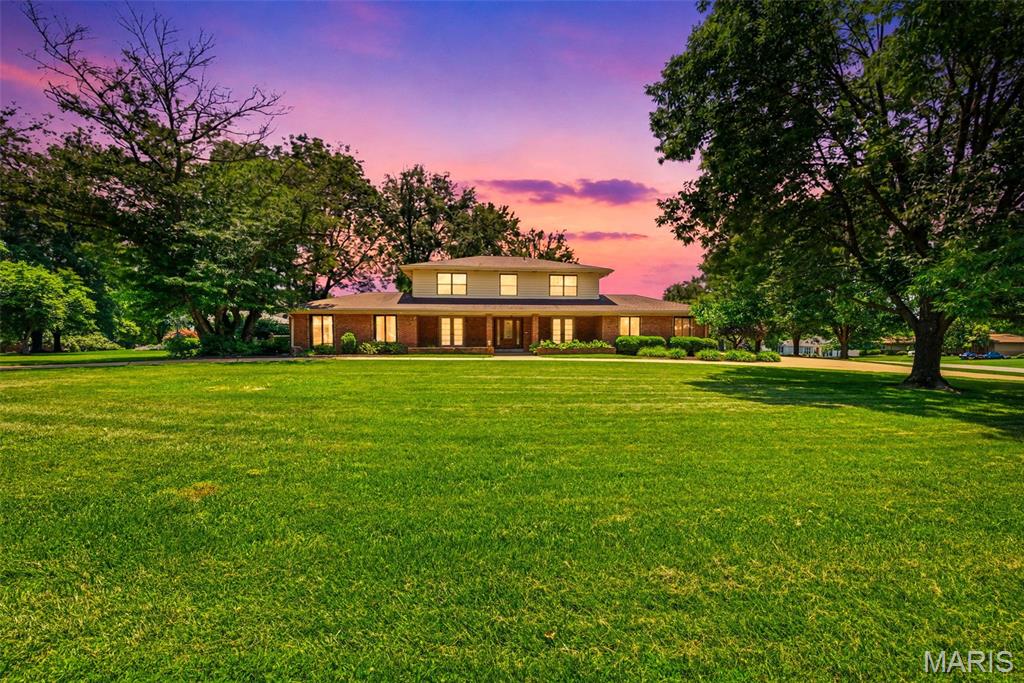 Elegance and timeless appeal define this stately Ladue Trails two-story, perfectly positioned on a level half-acre homesite. Impressive landscaping, a circle driveway, and a fully insulated attached 4-car garage offers abundant storage, hobby space, and parking. The covered front porch welcomes you through a decorative stained-glass entry door into a home filled with character and quality finishes. Hardwood floors flow throughout the main living areas, complemented by decorative ceramic tile flooring. The chef-inspired kitchen features a gas cooktop, pot filler, granite countertops, tile backsplash, abundant recessed lighting, 42" soft-close cabinetry, and a center island. Enjoy the convenience of a main-floor laundry/mudroom with utility sink. Spacious living areas include a cozy family room with fireplace and a sunken living room ideal for entertaining. Relax on the covered rear porch overlooking the expansive backyard. Upstairs, hardwood floors continue throughout, including the spacious primary suite with an updated bath featuring double vanity and large tiled shower. Additional highlights include Andersen casement windows, fluted trim, ceiling fans throughout, central vacuum, and extensive parking. A rare combination of elegance, functionality, and space in a highly desirable location!