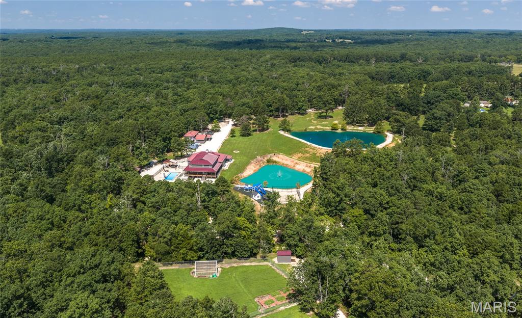 Discover a one-of-a-kind 125-acre retreat where luxury, functionality, and income potential come together in one extraordinary property. Whether you're searching for a private family estate, multi-generational homestead, working hobby farm, or investment opportunity, this remarkable compound is ready to deliver from day one.

The impressive main residence offers seven spacious bedrooms, four bathrooms, a dedicated office, multiple living areas, radiant heated floors, and thoughtfully designed flex spaces that adapt to your lifestyle. The walkout lower level features a kitchenette, full gym, additional bedroom, and separate living area, while the upstairs creates the perfect private retreat for extended family or guests. Quartz countertops, KitchenAid stainless steel appliances, a wood-burning fireplace, and a luxurious primary suite with a jetted soaking tub and private patio access elevate everyday living.

Beyond the main home, the possibilities continue with a beautifully updated 3-bedroom, 2-bath guest house complete with its own oversized garage, plus a massive 40x80 shop featuring two integrated bunkhouse living quarters—ideal for rental income, employees, guests, or recreational use. Outside, enjoy two fully stocked ponds, an in-ground pool and hot tub, a professional playground, fenced basketball court, climate-controlled chicken coop, and extensive power distribution throughout the property, providing exceptional flexibility for future expansion.

Rarely does a property offer this level of space, infrastructure, and versatility in one package. Whether you're creating a family legacy, operating a business from home, or generating multiple income streams, this extraordinary rural compound is ready to exceed your expectations. Schedule your private tour today and experience everything this incredible property has to offer.