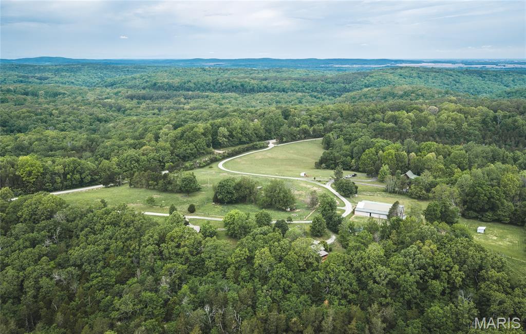This is a rare opportunity to own a turnkey short-term rental and event property set on 88 acres in the heart of Southern Illinois’ outdoor recreation corridor. Located within the Shawnee National Forest and adjoining it on three sides, this property offers unmatched access, privacy, and natural beauty. The property features a lodge-style home with exposed beams and tall vaulted ceilings, creating a warm and inviting space that fits perfectly with the surrounding landscape. An 80x70 pole barn has been partially finished for commercial use, including a full commercial kitchen, two bathrooms, and a large lounge and recreation area—ideal for hosting events, group gatherings, or expanding business operations. There are seven individual rental units currently in operation, generating consistent income with nightly rates ranging from $126 to $260 and an average nightly rate of approximately $183. The layout allows for flexibility in accommodating weekend travelers, outdoor enthusiasts, and larger group bookings. The location is a major draw. Surrounded by the Shawnee National Forest, the property provides direct access to miles of trails and is well suited for a horse camp, hiking basecamp, or destination retreat. Nearby attractions include Rim Rock Trail, Garden of the Gods, Pounds Hollow Lake, and Cave-In-Rock State Park, along with scenic springs, waterfalls, and endless opportunities for hunting, fishing, and hiking. This property combines strong income potential, functional improvements, and a premier location into a unique investment opportunity in one of the most sought-after outdoor regions in the Midwest.