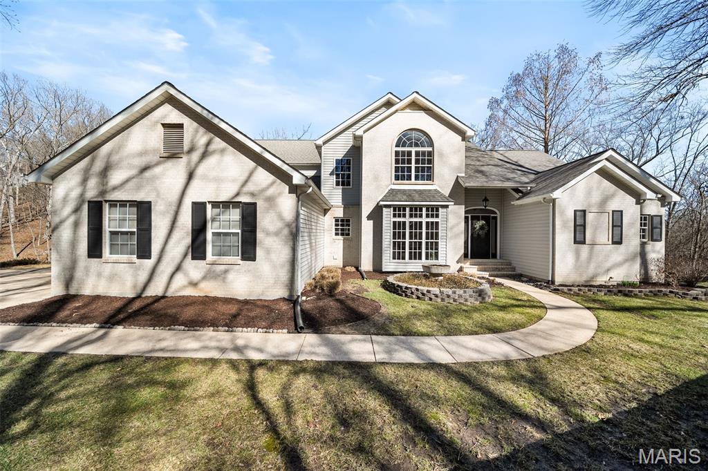 Tucked away on 3 breathtaking acres in beautiful Wildwood, 2408 Redbud Valley Drive is a private luxury retreat offering the perfect balance of seclusion and convenience. This fully renovated and reimagined 5 bed, 5 bath estate showcases elevated design, top-tier finishes, and energy-efficient geothermal heating and cooling.

An impressive marble entry opens to soaring ceilings and three stories of floor-to-ceiling windows, creating a dramatic first impression while framing serene views of the manicured lawn, mature trees, patio, and picturesque backyard pond. The home lives with an incredible sense of openness and light, offering sweeping sightlines from the third floor all the way to the walk-out lower level. Walls of windows and soaring ceilings create a breathtaking, airy atmosphere where every level feels connected and immersed in the surrounding natural beauty.

Newly refinished hardwood floors span the main level. The primary suite is a true sanctuary with tall ceilings and a spa-inspired bath featuring high-end finishes, designer details, and a generous walk-in closet — a private retreat designed for comfort and sophistication.

Designed for both everyday living and elevated entertaining, the eat-in chef’s kitchen features all new appliances including a smart range, custom hood, additional wall oven, granite countertops, custom cabinetry, and a large island with bar seating. The breakfast room adjoins a cozy, tucked-away family room with fireplace, creating an intimate yet functional gathering space.

Upstairs offers three spacious bedrooms, including a newly added en suite, plus a loft ideal for relaxation or play.

The finished walk-out lower level is an entertainer’s dream, complete with fireplace lounge, game area, fully renovated wet bar, updated full bath, private bedroom or fitness suite with separate access, sunroom, and a theater room ready for your custom vision. An extraordinary Wildwood estate where luxury meets nature.