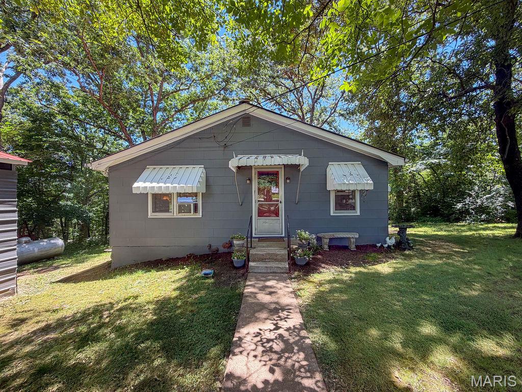 Welcome home to this 2-bedroom, 1-bath ranch nestled on a peaceful 1-acre lot surrounded by mature shade trees. Offering approximately 976 sq. ft. of living space, this inviting home blends country charm with modern comfort and is the perfect opportunity for first-time buyers, downsizers, or anyone seeking a tranquil setting just minutes from town. Step inside to discover living area with updated flooring and abundant natural light. The kitchen features beautiful cabinetry, newer stainless steel appliances, generous counter space, and a convenient dining area—ideal for everyday living and entertaining. Both bedrooms are comfortably sized, while the updated bathroom showcases stylish finishes and timeless appeal. Outside, you'll love the picturesque setting complete with towering trees, a level yard, and a detached outbuilding perfect for storage, hobbies, or a workshop. 
Enjoy quiet mornings on the property, evenings under the stars, and the peaceful atmosphere that only country living can provide.  Located in the Festus School District and situated on a full acre, this move-in ready home offers the perfect combination of privacy, charm, and convenience. Don't miss your chance to own this adorable country retreat.