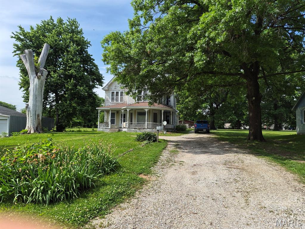 Own a part of history here!  This classic 4-bed, 2-bath home with large rooms has plenty of space for a growing family.  Unique features include an original stained-glass window, an etched glass window, folding wood doors, hardwood floors and the original wood banister stairway. There is one bedroom on the main floor and three spacious bedrooms upstairs. The upstairs bathroom has two entry doors and adjoins one bedroom. The main floor bathroom is located to one side of the kitchen and the utility room adjoins the other side that leads to the large back yard. You don't find wrap-around porches like this every day! The perfect spot for morning coffee & evening visits.  Most of the windows have been replaced.  City utilities are in place, and the propane tank is owned.  You'll appreciate the nearly 1/2 acre yard, mature trees, perennials in bloom, spacious lot & storage shed.  All of this conveniently located a block from Scotland County Hospital.