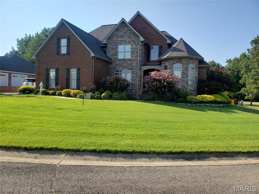 Beautiful custom built French manor style brick and stone two story home with walkout finished lower level.  Property has two lots with a hundred and ninety feet curb and road finished frontage.  The main level features Tiger wood flooring and a gas log fireplace. The master bedroom includes ensuite Jacuzzi tub with 2 vanities and 2 walk in closets.  The upper level features 3 bedrooms, one extra large and a full bath.  The lower level is a complete living area with full kitchen, a fabulous family room, bedroom, full bathroom, media room, storage room and a 13×22 workshop /storage garage.  Two new Lennox heat and air units were installed in 2024, along with a new 50 gallon water heater.  Also added is a large 72 inch fan in living room cathedral ceiling.  New GE kitchen appliances installed in 2024.  There is a view of the pond from the front of the house. This home was the development builders personal home that features many custom extras.