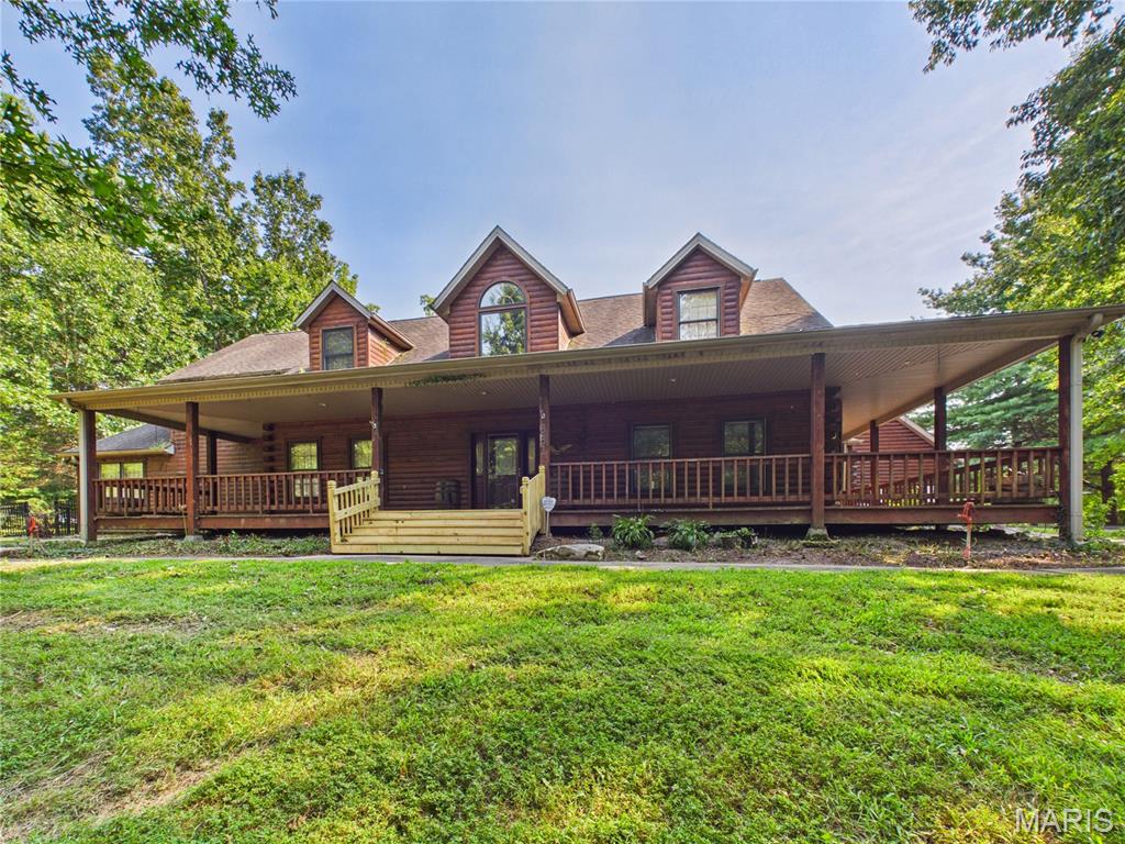 Escape to your own private retreat at 331 Pine Log Lane! Nestled on 6.96 scenic acres, this custom log cabin offers rustic charm, spacious living, and incredible amenities with over 5800 finished square feet, including 5 bedrooms, 3 full baths, and 2 half baths. The main level features a spacious open-concept kitchen, dining, and living area with soaring vaulted ceilings and access to a wraparound covered deck overlooking the in-ground chlorine pool with an automatic cover. The kitchen has large center island, gas cooktop, stainless steel appliances, and abundant cabinet and countertop space. The spacious main level primary suite is its own retreat with a cozy fireplace, two walk-in closets, double vanities, a jetted tub, and a walk-in shower, adjoining an additional cozy office. You'll also appreciate the convenience of a main level laundry, plenty of pantry storage, and two half baths for guests. Upstairs, two oversized bedrooms share a full hall bath with dual sinks.
The walkout basement offers endless possibilities and living space with an additional bedroom featuring an egress window, a full bath, family room with a wood-burning fireplace, kitchenette, wine cellar, multiple bonus rooms perfect for hobbies, offices, or a home gym, plus generous storage throughout.
Need space for projects or equipment? This property delivers! A large workshop beneath the garage with its own electrical panel connects to another shop with a garage door, two additional garage bays, and a separate workshop that was previously used as a dog kennel, complete with a large utility sink, half bath, its own water heater, HVAC, and a wood-burning stove.
Outside, you'll find everything you need to enjoy country living, including a pond, fenced chicken coop, peach and apple trees, and two barns—one newly built in 2021. A whole home solar generator adds efficiency and peace of mind, with solar panels providing up to 40% of the power supply to the home. If you've been dreaming of a private country property with room to live, work, entertain, and enjoy the outdoors, this one-of-a-kind log home is a must-see!