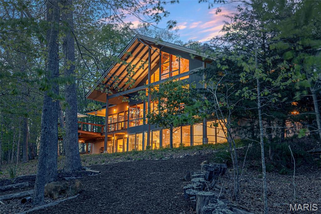Designed by award-winning St. Louis architect Gary Glenn and featured in St Louis Magazine, this luxury lakefront residence on Innsbrook's Lake Alpine was created as a true retreat—offering privacy, ease, and uninterrupted connection to the water. Positioned on approximately 125 feet of shoreline overlooking the largest basin of Lake Alpine, the home features a full rear glass elevation on both levels, capturing panoramic water views and filling the interior with natural light. The layout is intentionally simple and livable, with full main-level living including a primary suite, laundry, kitchen, and gathering spaces—all designed for effortless weekends at the lake and easy entertaining. An elevator provides convenient access between levels. The primary suite is spacious and functional, offering a steam shower, soaking tub, dual closets, and integrated laundry. The open living spaces include a view-oriented kitchen, multiple seating areas, a dedicated dining space, and a gas fireplace conversation area, along with a sunroom featuring a Rumford wood-burning fireplace. The lower level is designed for guests, including an en suite bedroom, additional flexible bedrooms or office/fitness spaces, a media/game room, and heated floors throughout. Each lower-level room opens directly to the exterior and features full glass walls, continuing the lake views throughout the home. Additional features include new roof (2025), geothermal HVAC with four-zone climate control, fiber-optic internet, three-car garage with EV charging, and a concrete dock with electric service. Separately enjoy a spacious lakeside observation deck. Don't wait long to see this Innsbrook luxury home on one of the most coveted lots on Lake Alpine.